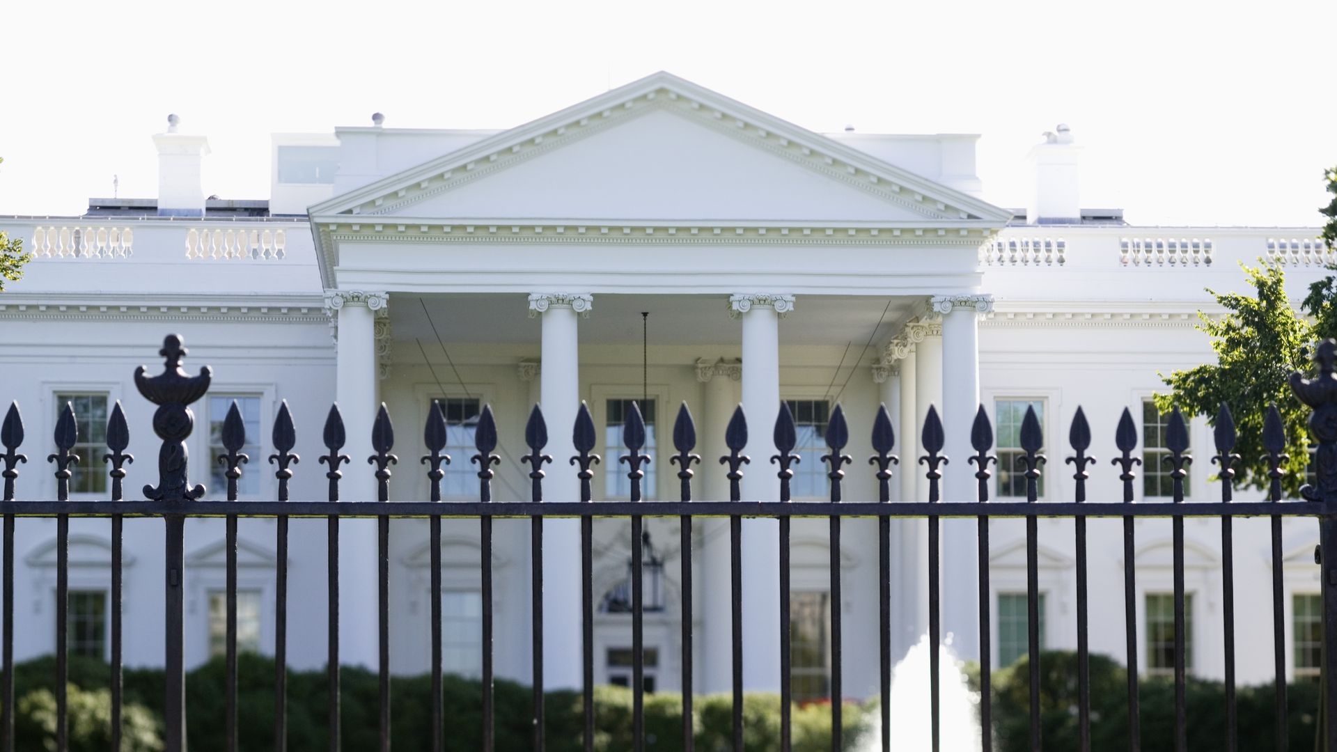 Upclose photo of the White House with a fence in front.