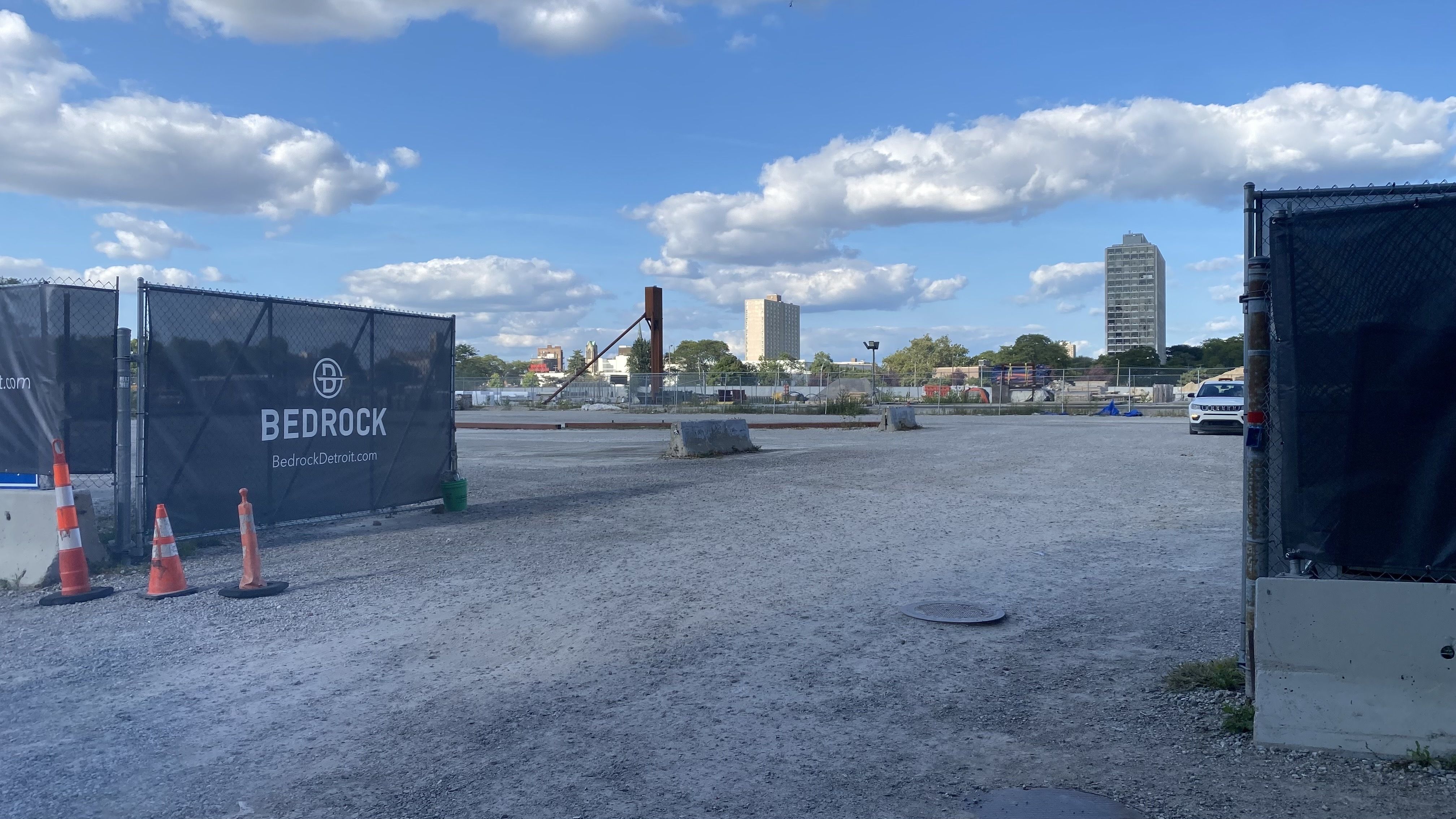 The gravel-floored vacant former jail site, with a Bedrock scrim wrapped around it.