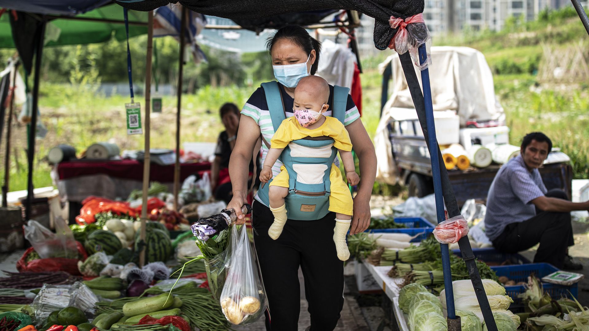 A woman carrying her child buys vegetables at an open market on May 31, 2021 in Wuhan, China.