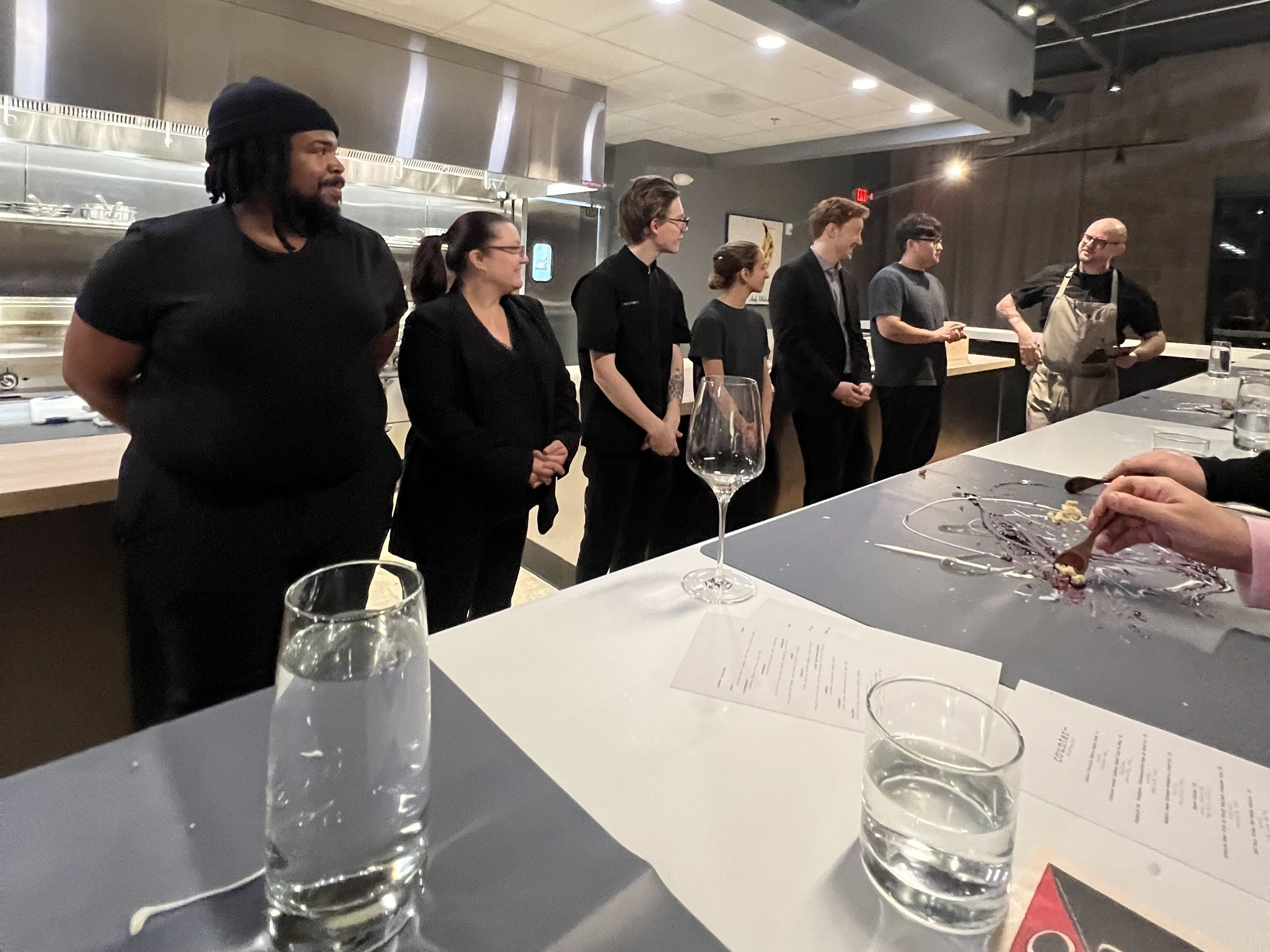 seven people stand in front of a kitchen