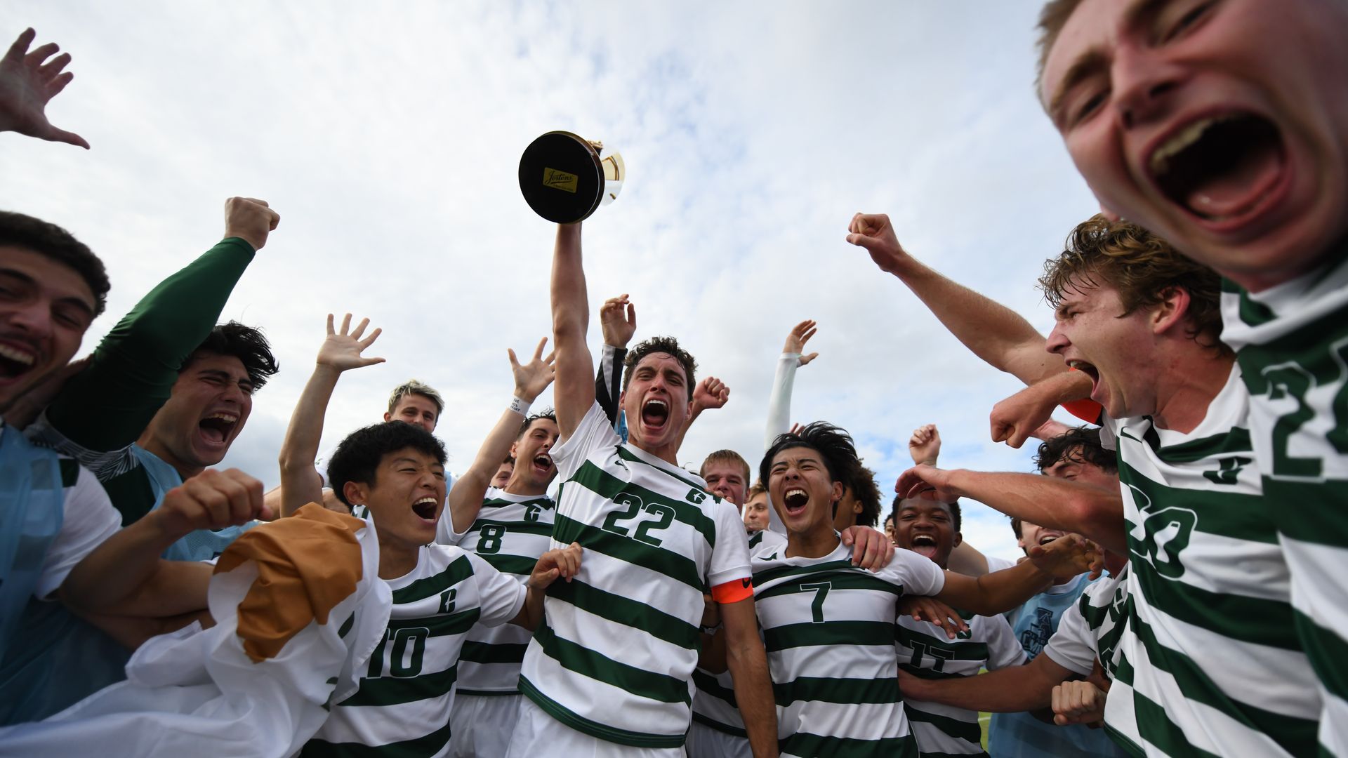 Charlotte 49ers men's soccer hoist the conference tournament trophy in the air after their win.