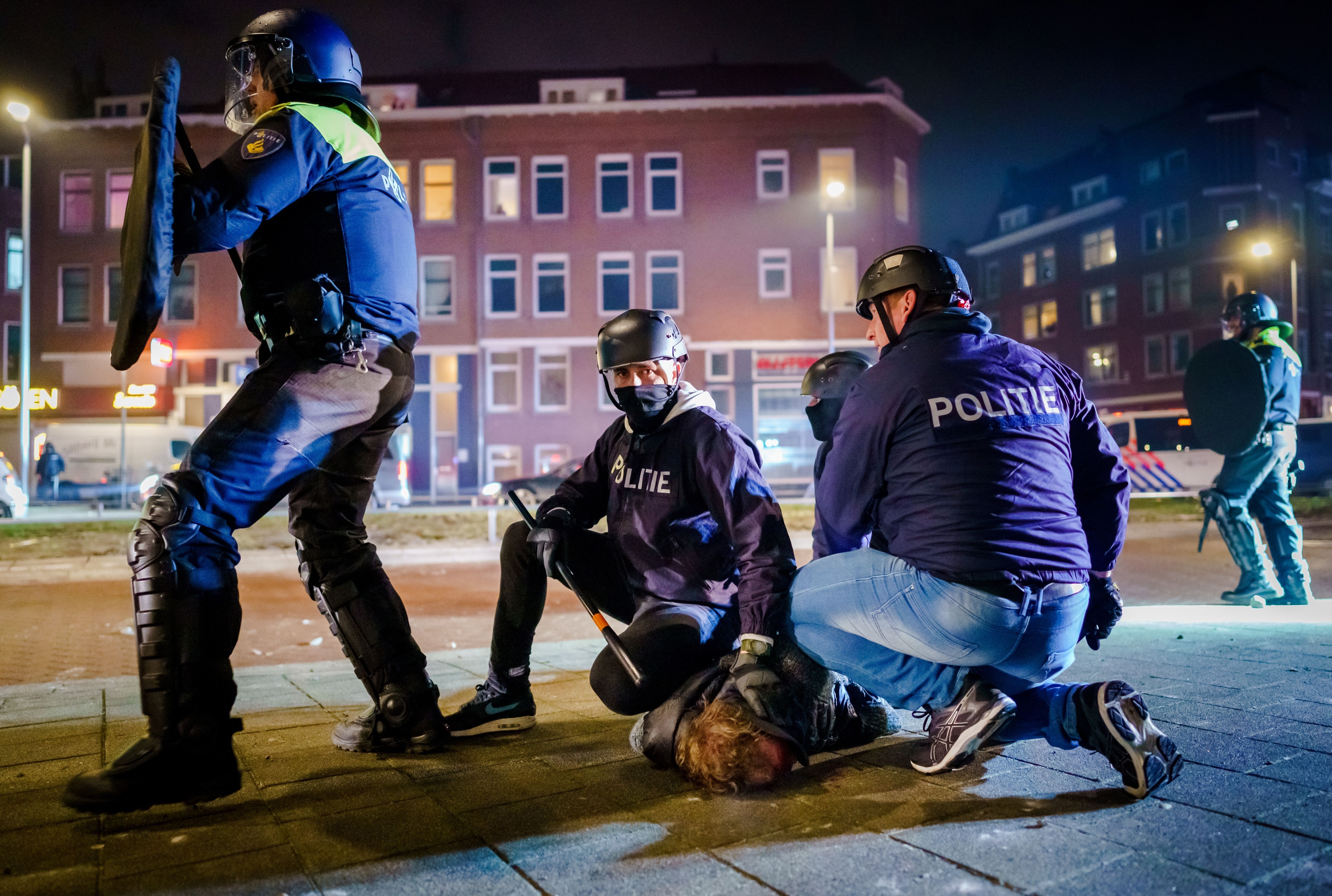 Photo of riot police holding a protester face down in the ground