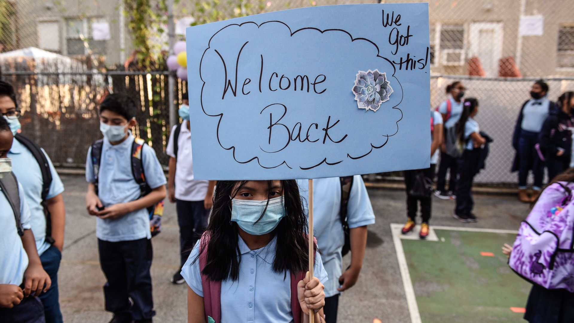 A girl holding a "welcome back" sign