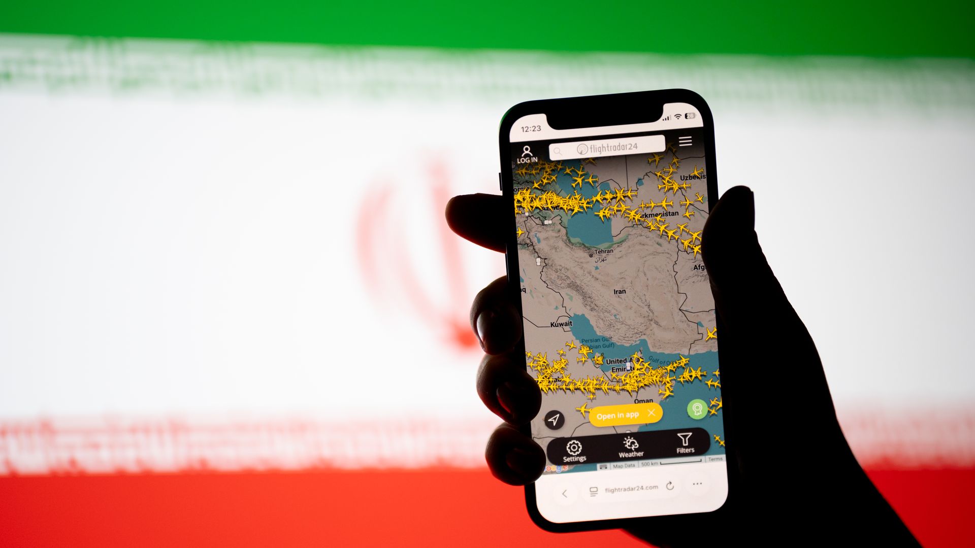 The Flightradar24 website displays on a mobile phone showing empty skies due to closed Iranian airspace, and the national flag of Iran appears on a computer screen, in Krakow, Poland, on March 3, 2026. Civil aviation comes to a halt across the region as Iran extends its airspace closure.