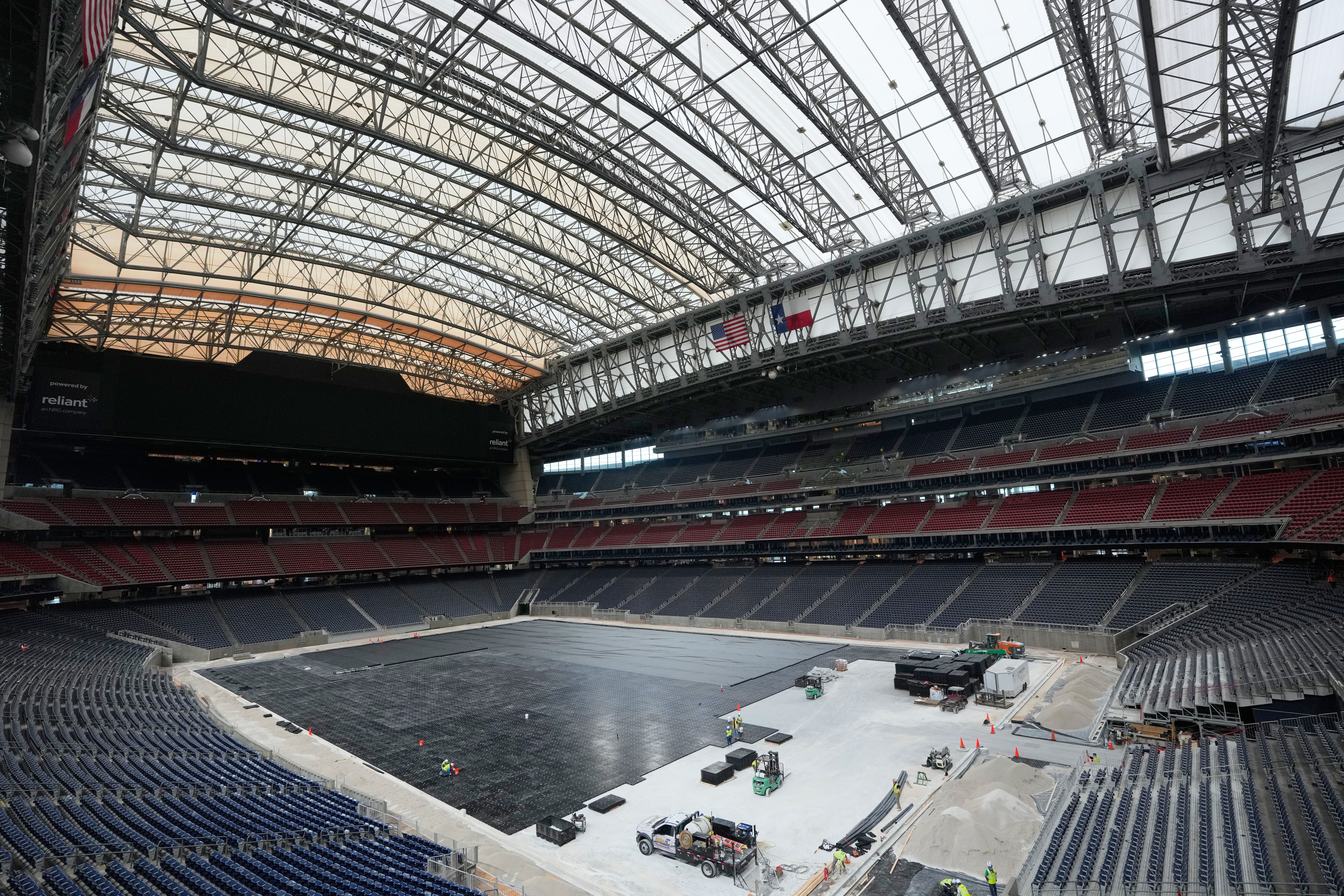 Workers install the first layer of the new playing surface for the World Cup at Houston Stadium, where the Texans play.