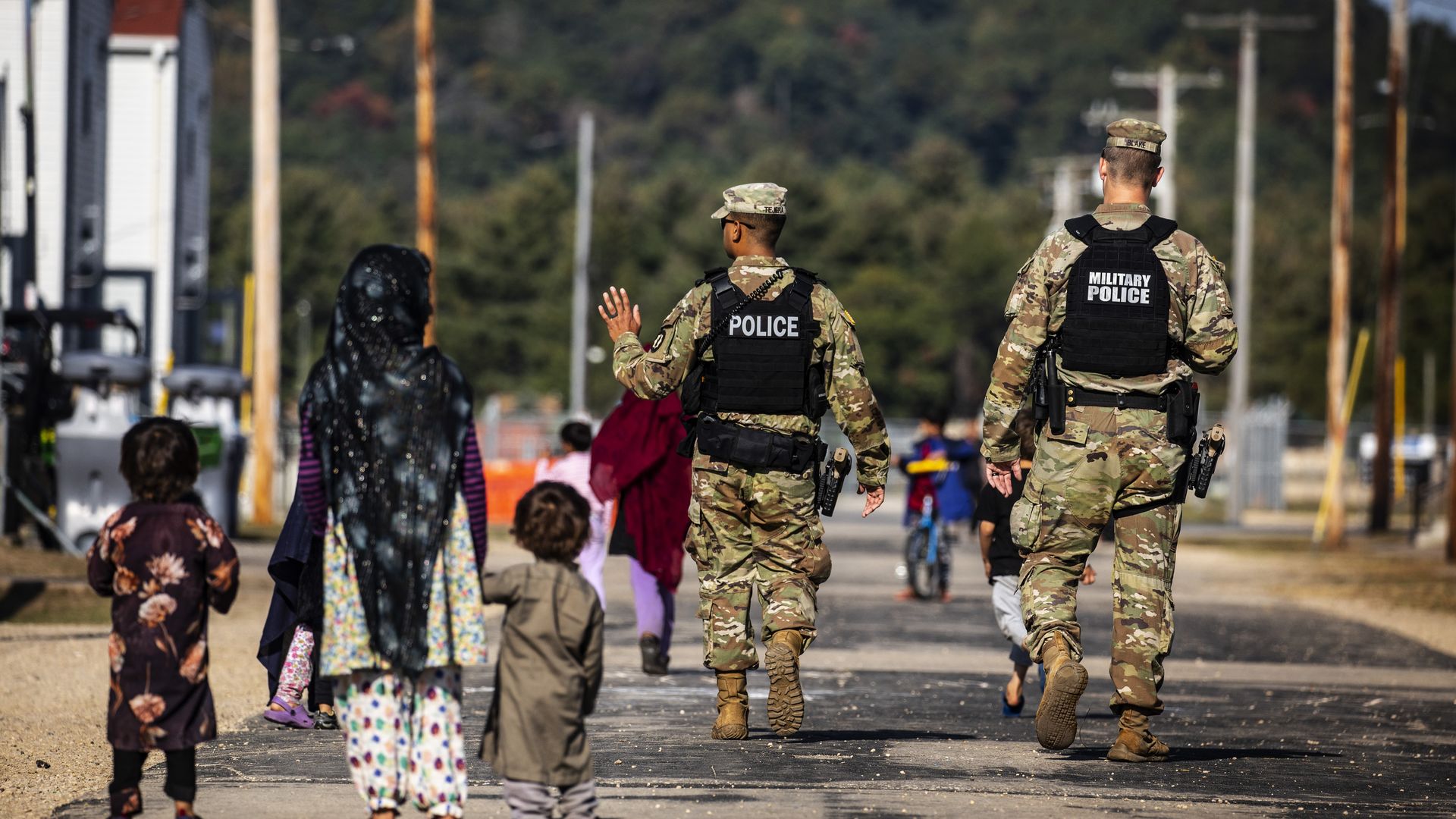 U.S. military police walking past Afghan refugees at an Army base in Ft. McCoy, Wisconsin, in September 2021.
