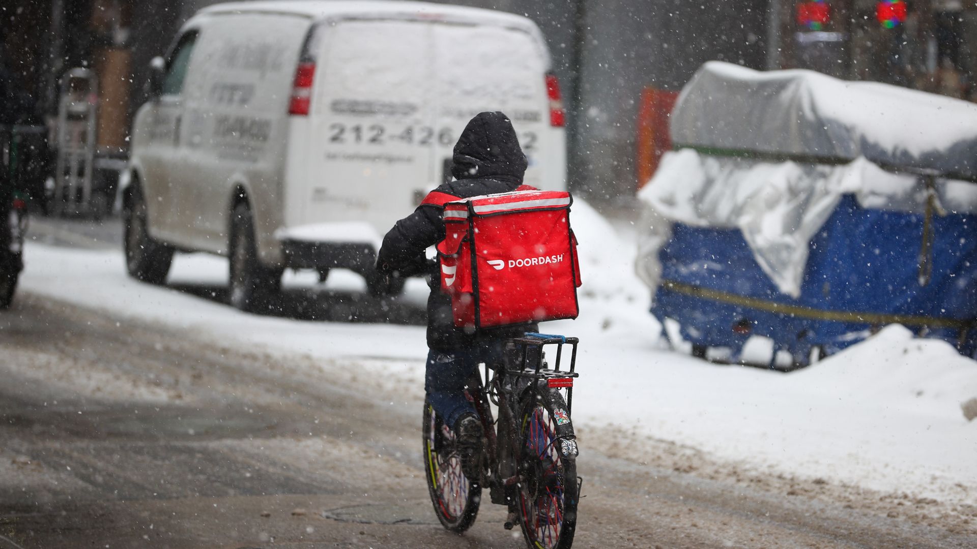 A food delivery guy with bicycle is seen as snowfall blankets the Times Square