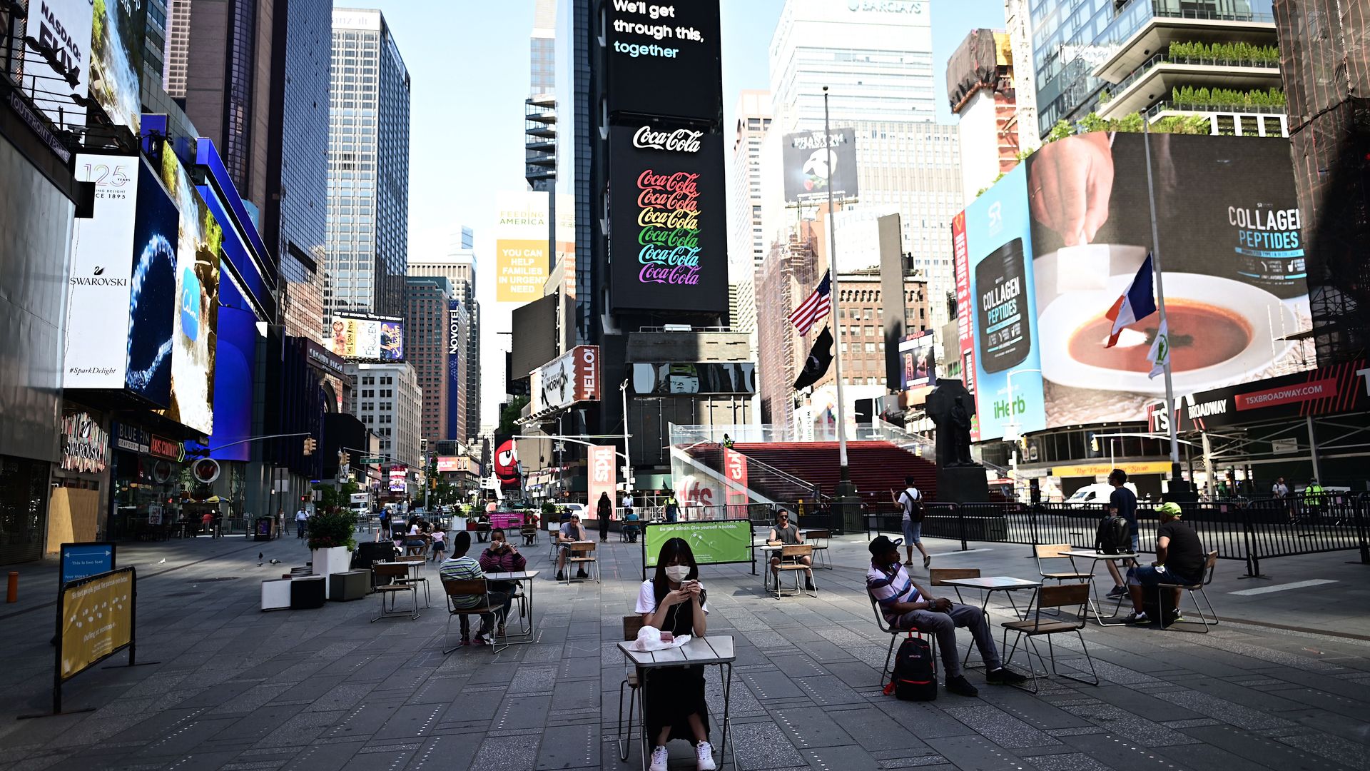 People sit on tables, respecting social distancing at Times Square as New York City enters phase two of reopening June 22