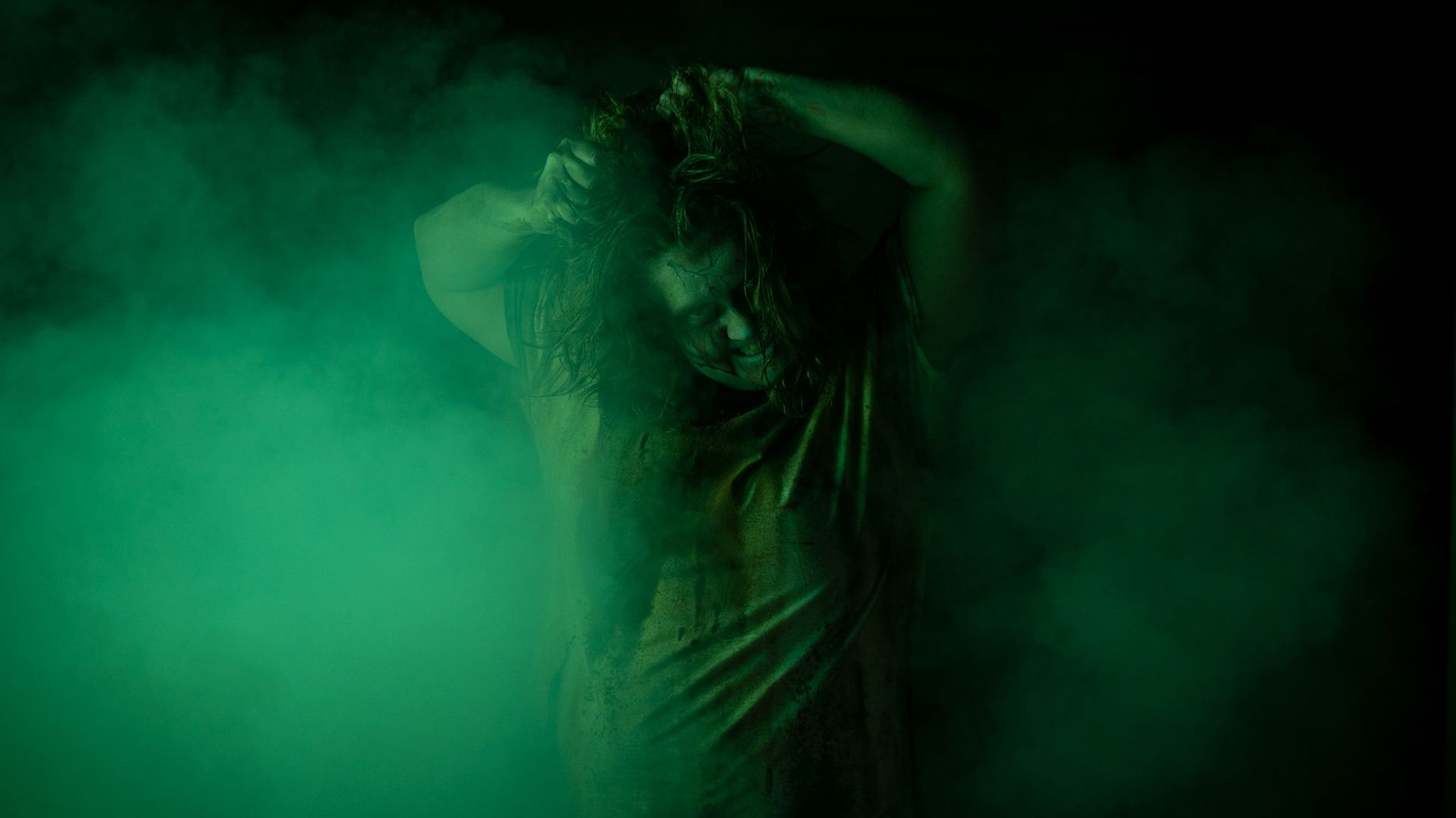 A Zombiezi Bay haunted house zombie poses amid green smoke