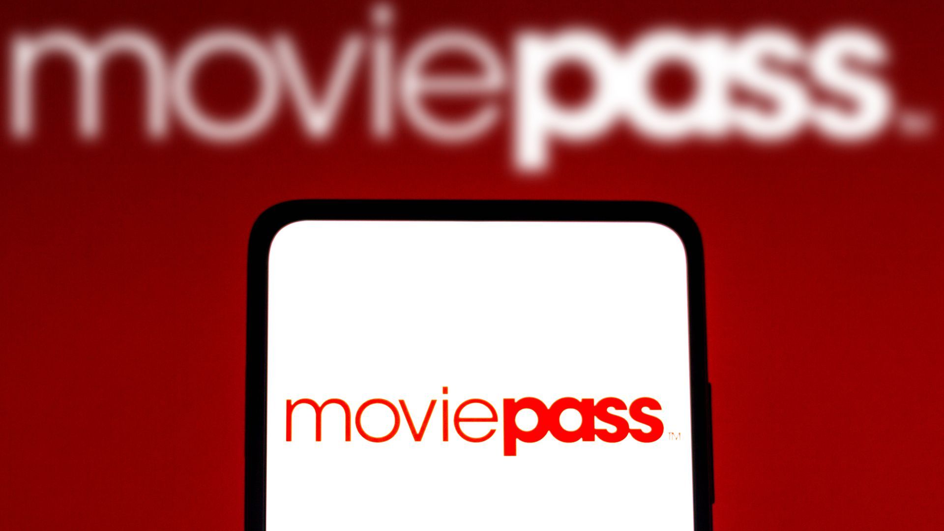 MoviePass logo on a phone in front of a red background with the company logo.