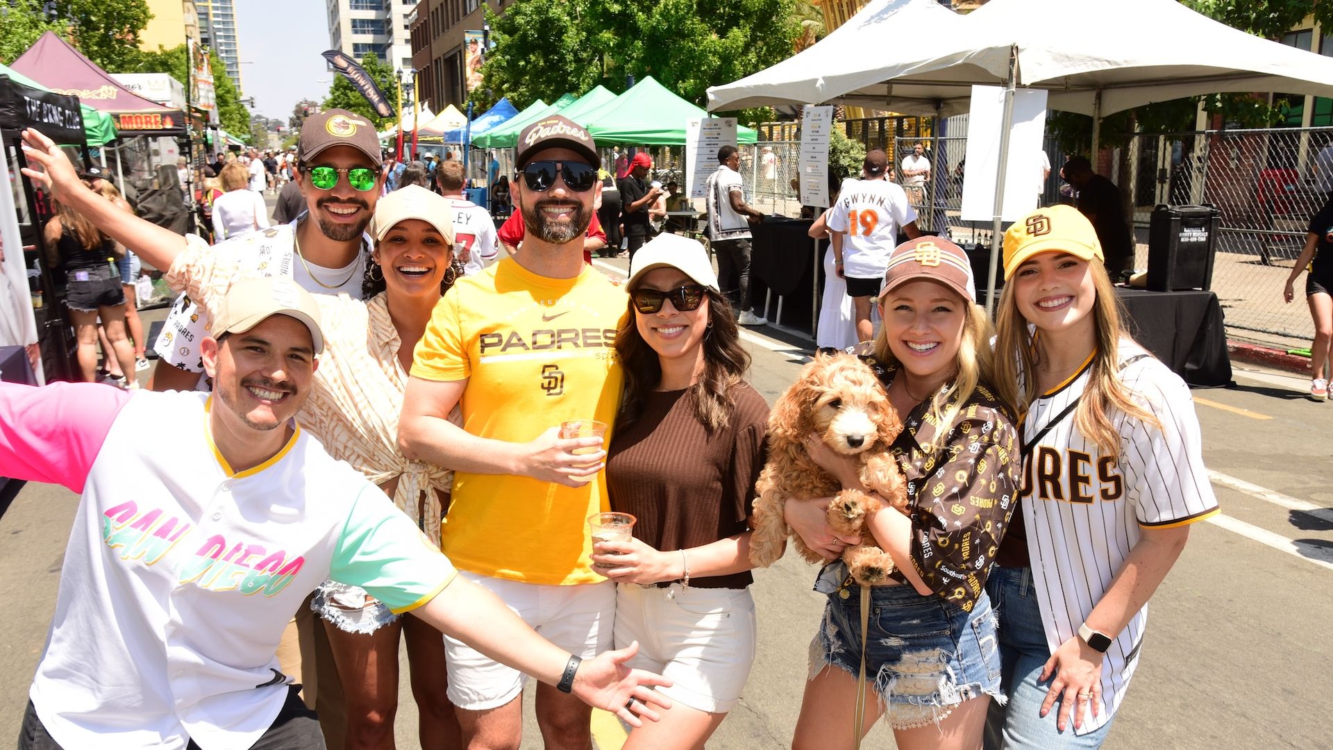 A group of padres fans pose for a photo at a street festival. 