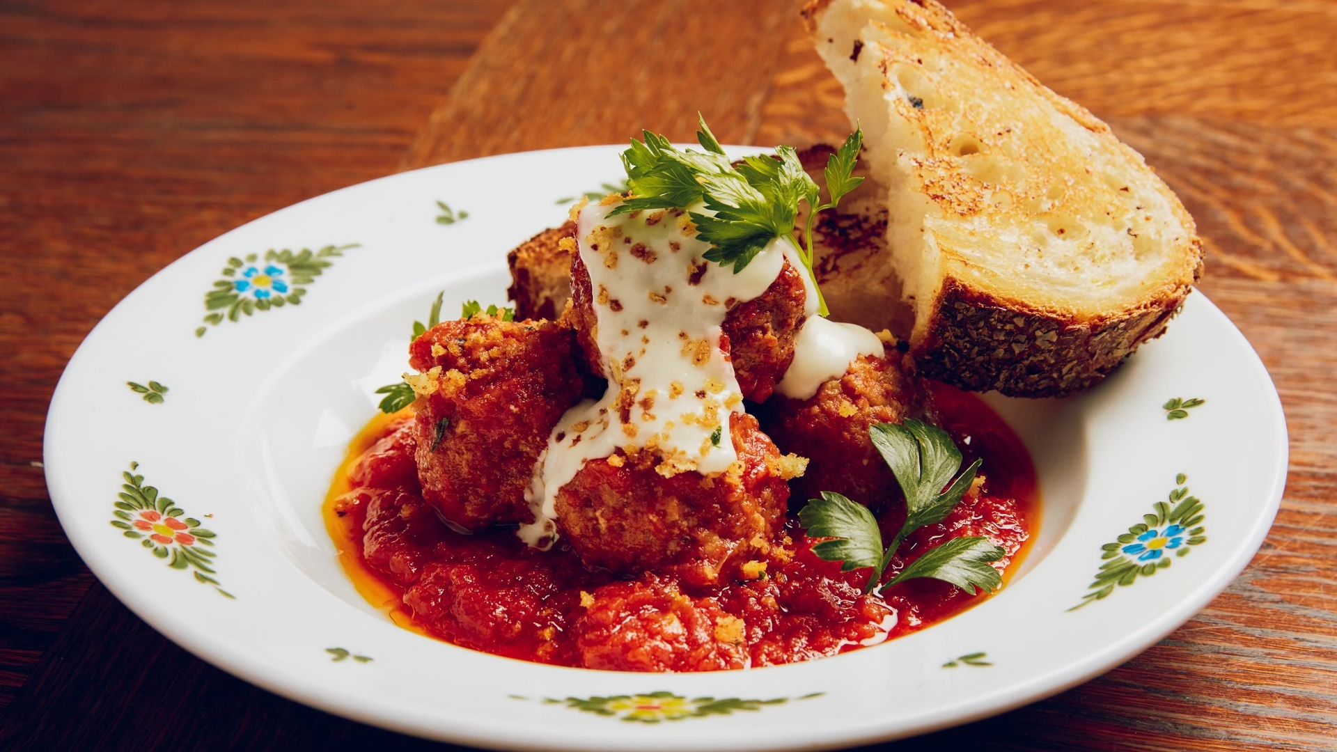 A bowl with meatballs in marinara sauce and toast