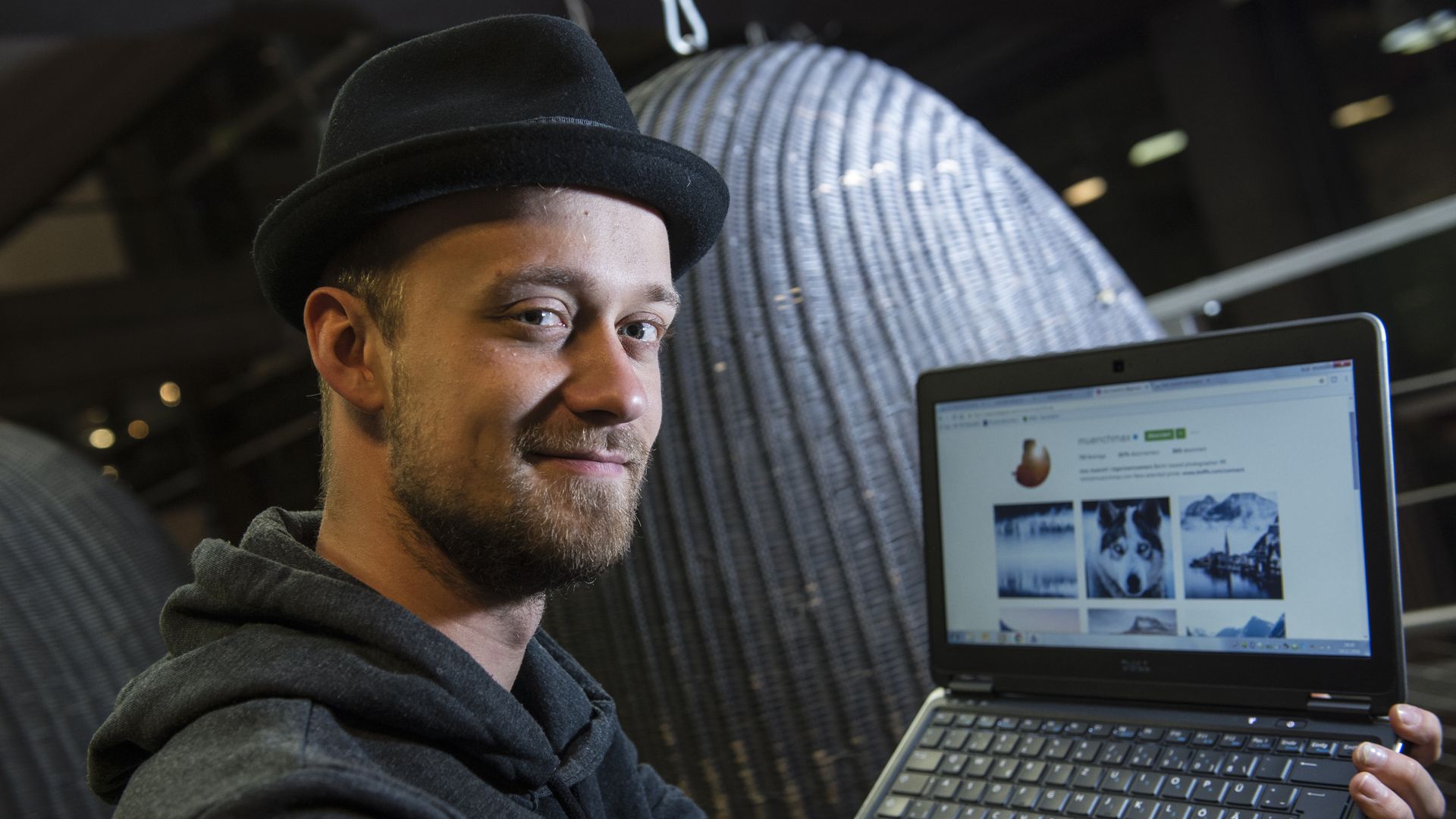 A man in a fedora shows off a laptop that's open to Instagram