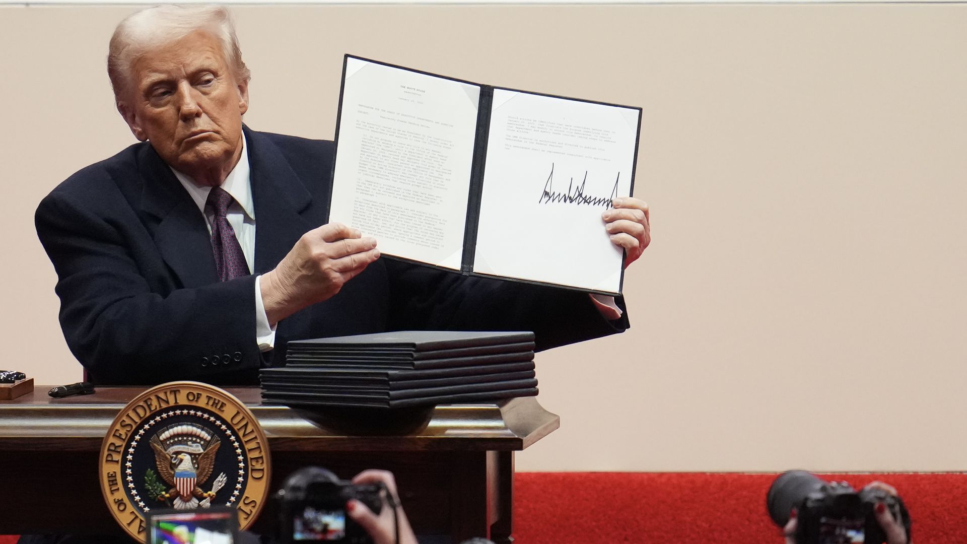 President Donald Trump holding a signed executive order. 