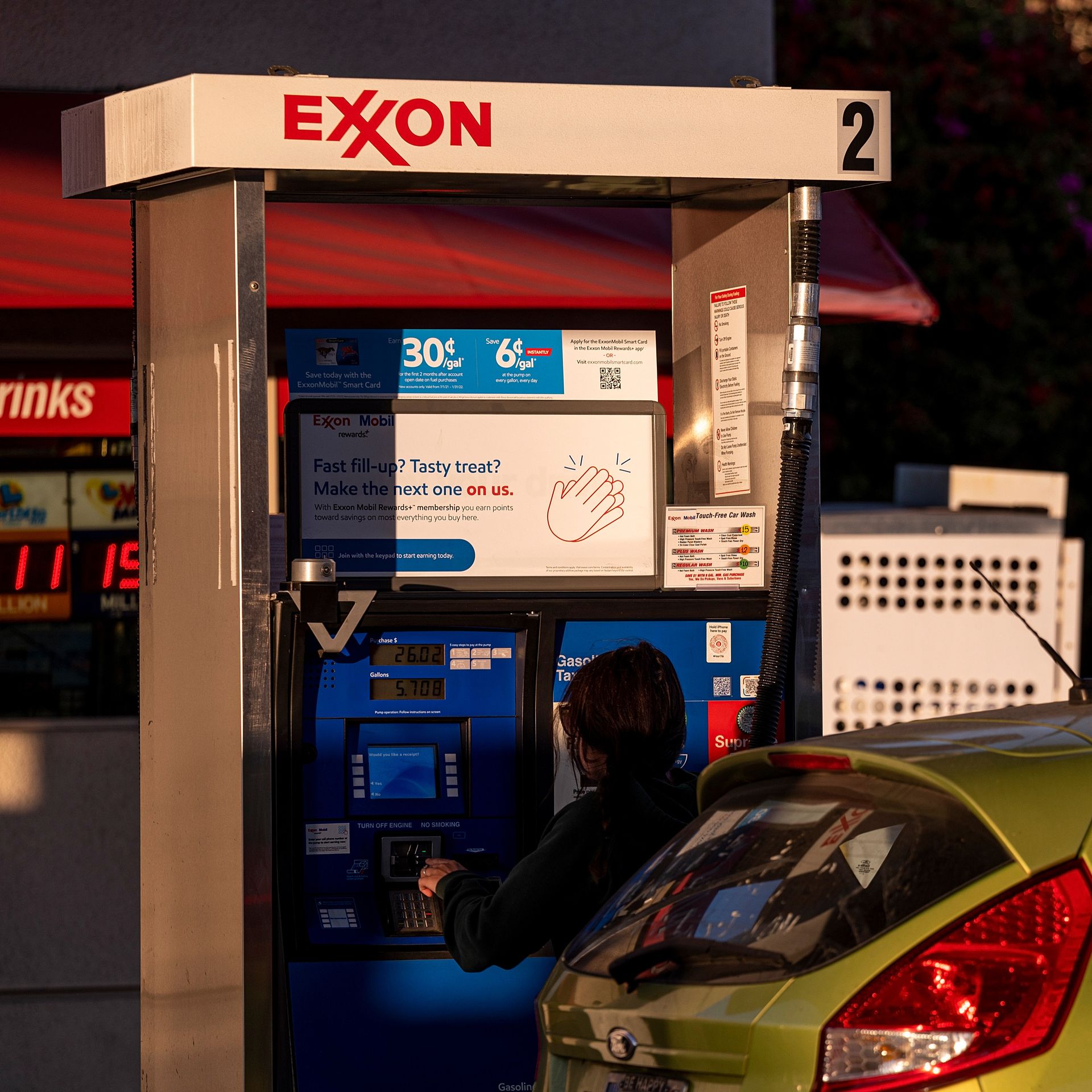 A woman fills up her car with gas at an Exxon gas station.