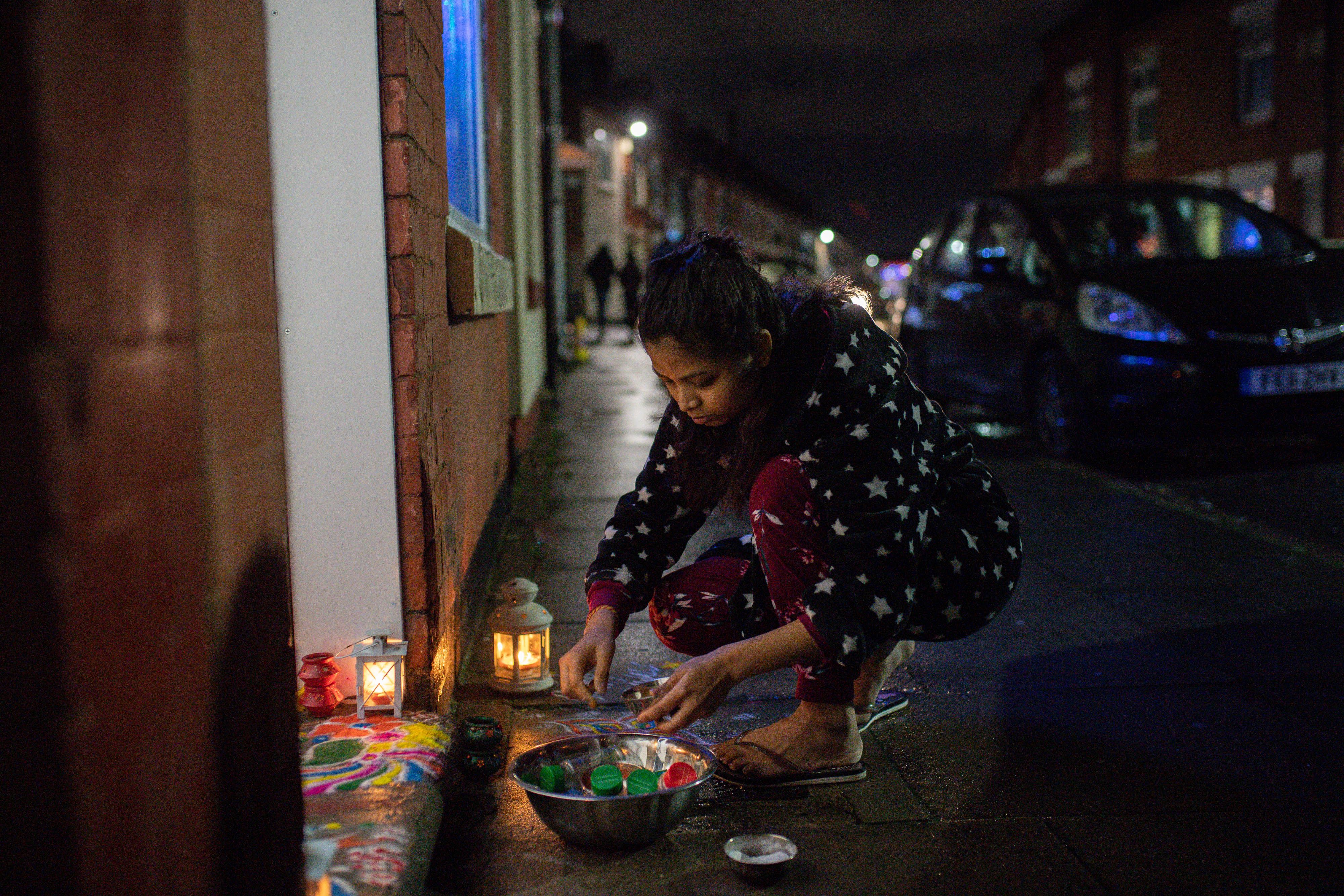 A lady decorates her doorstep during Dawali celebrations in Leicester this evening