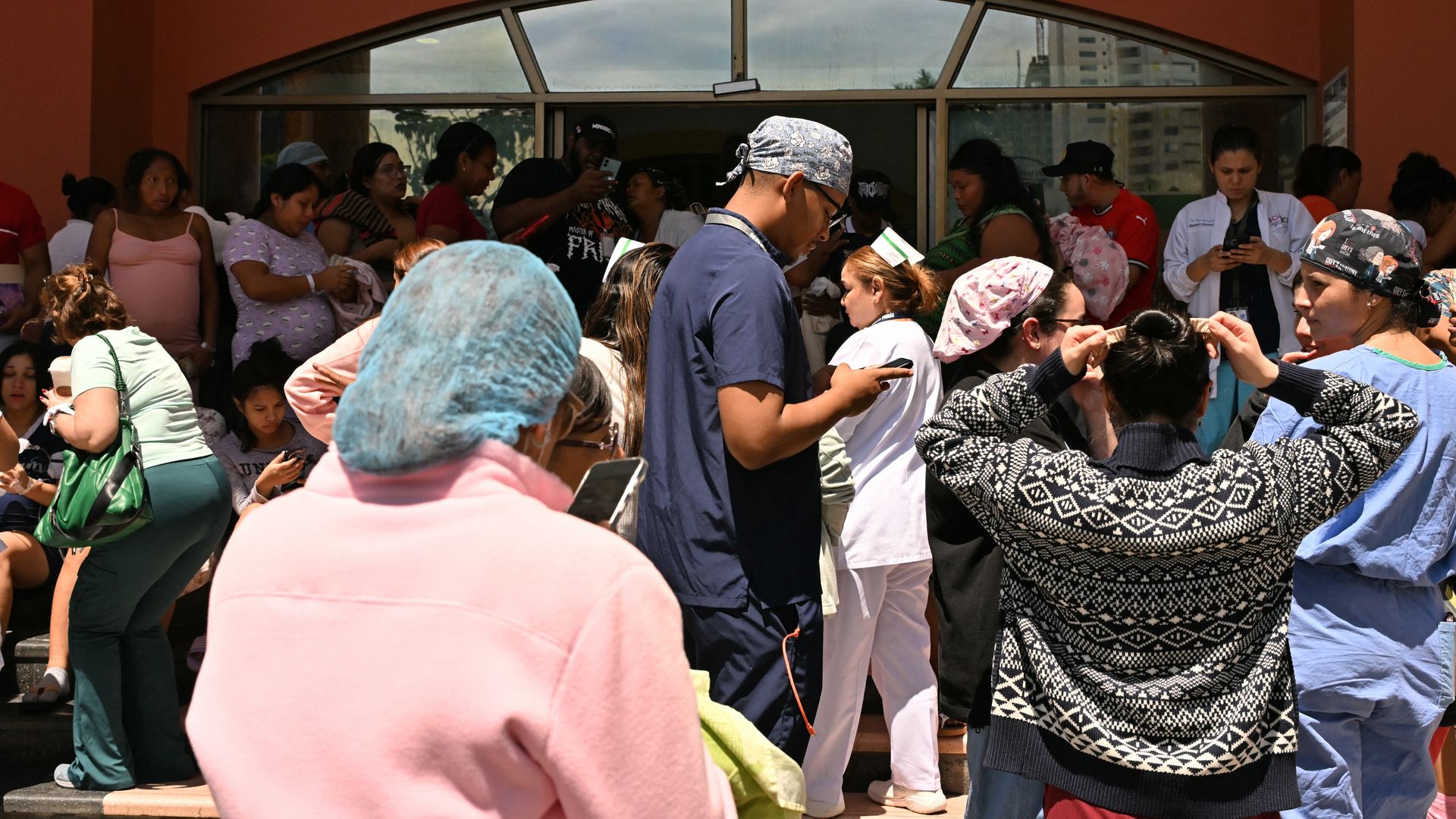 People, some in scrubs and head coverings, stand outside of a hospital after a severe magnitude earthquake hit Panama.