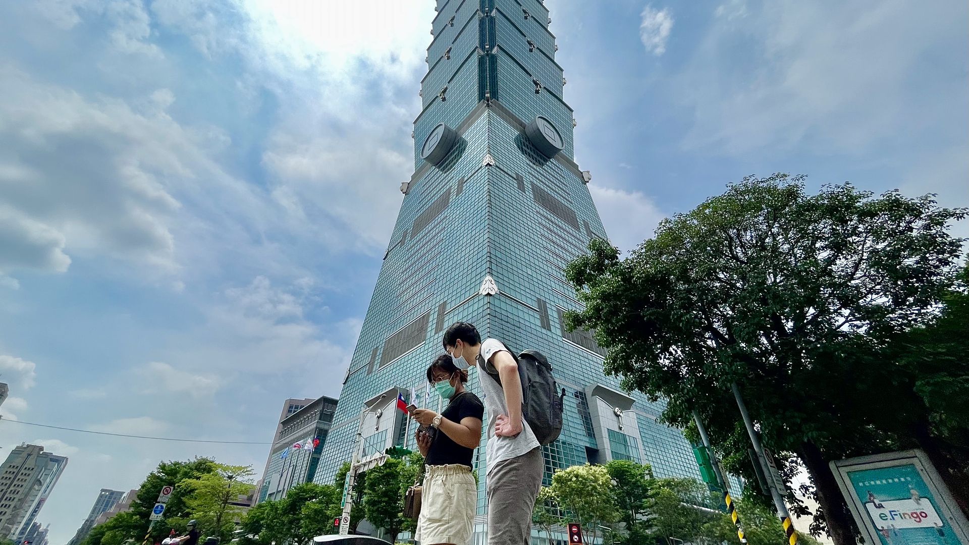 People wearing face masks walk past Taipei 101, a landmark in Taipei, amid a surge of locally acquired cases of Covid-19