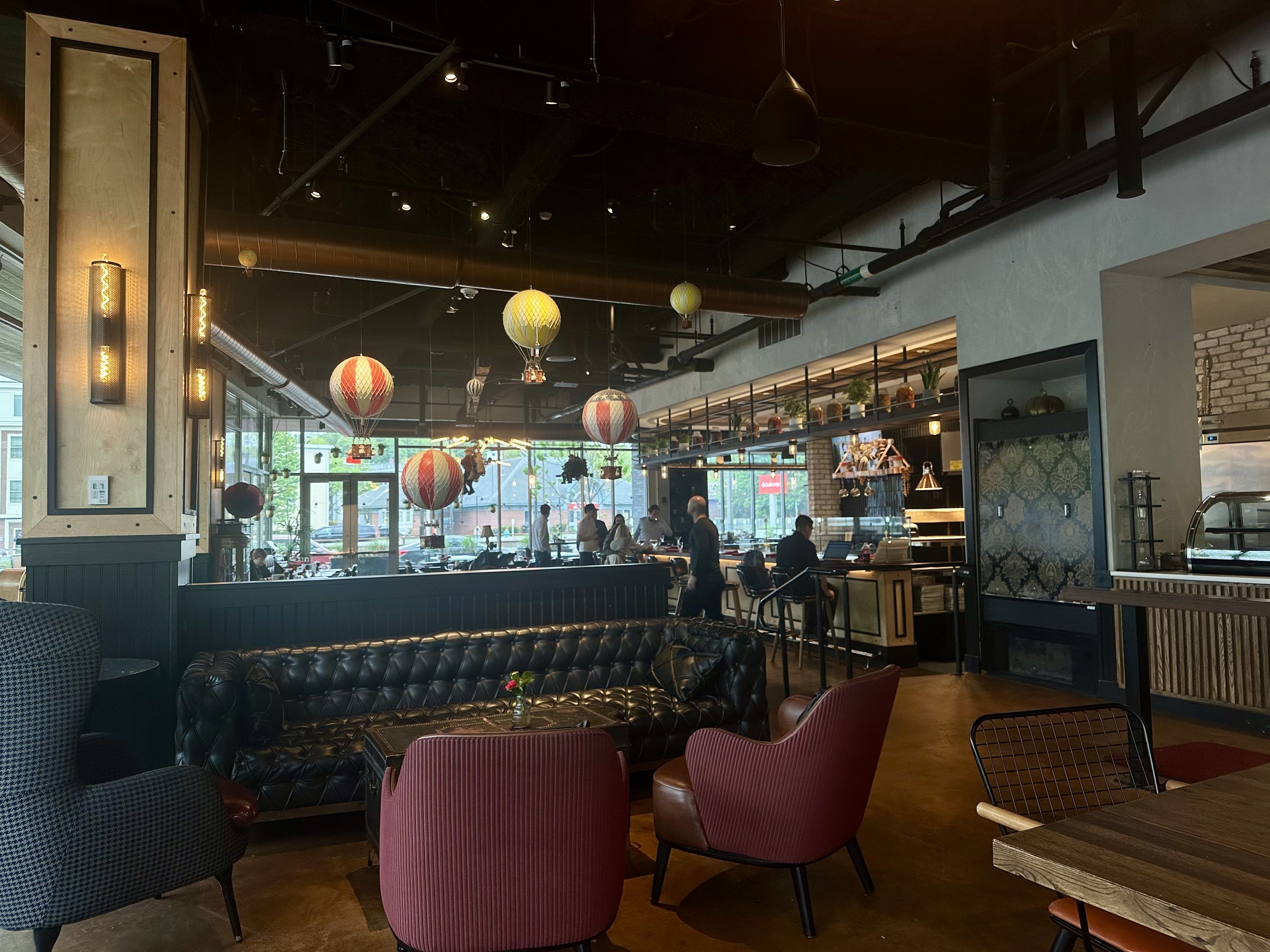 Inside Tradesman Coffee Shop & Pizza Bar in Charlestown, which has a longe couch, armchairs in the cafe area and a bar counter and tables behind the couch.