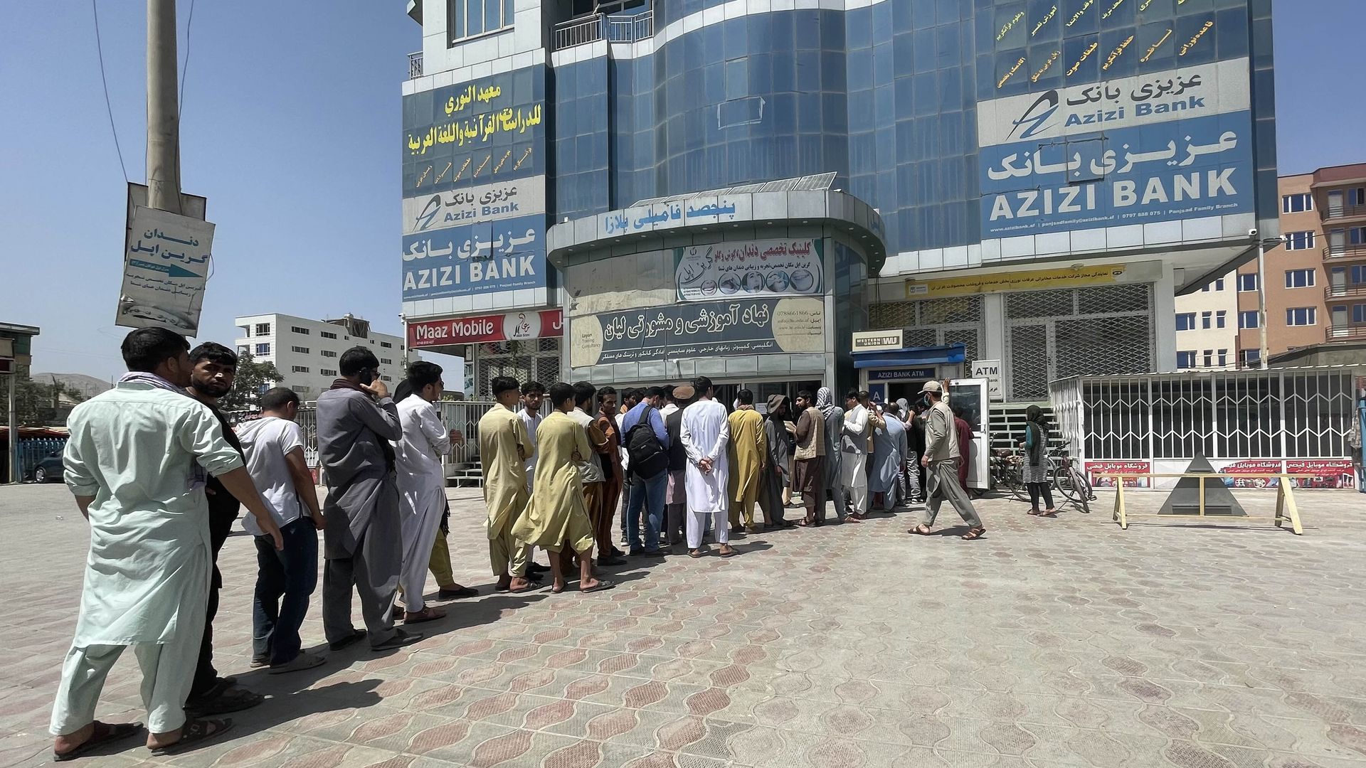 Afghan people line up outside a bank to get cash as the Taliban take Kabul.