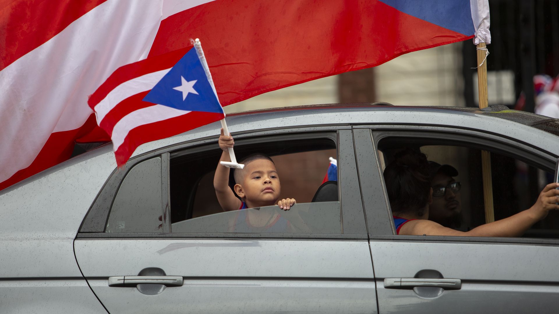 A child holds a puerto rican flag out the window of a parade car during the Chicago's 41st Annual Puerto Rican Pride Parade in Humboldt Park Chicago, on June 15, 2019.