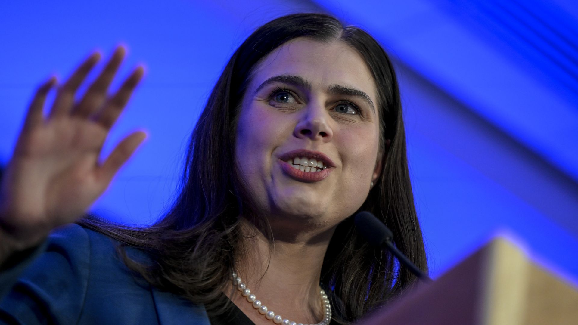 A woman smiles and waves.