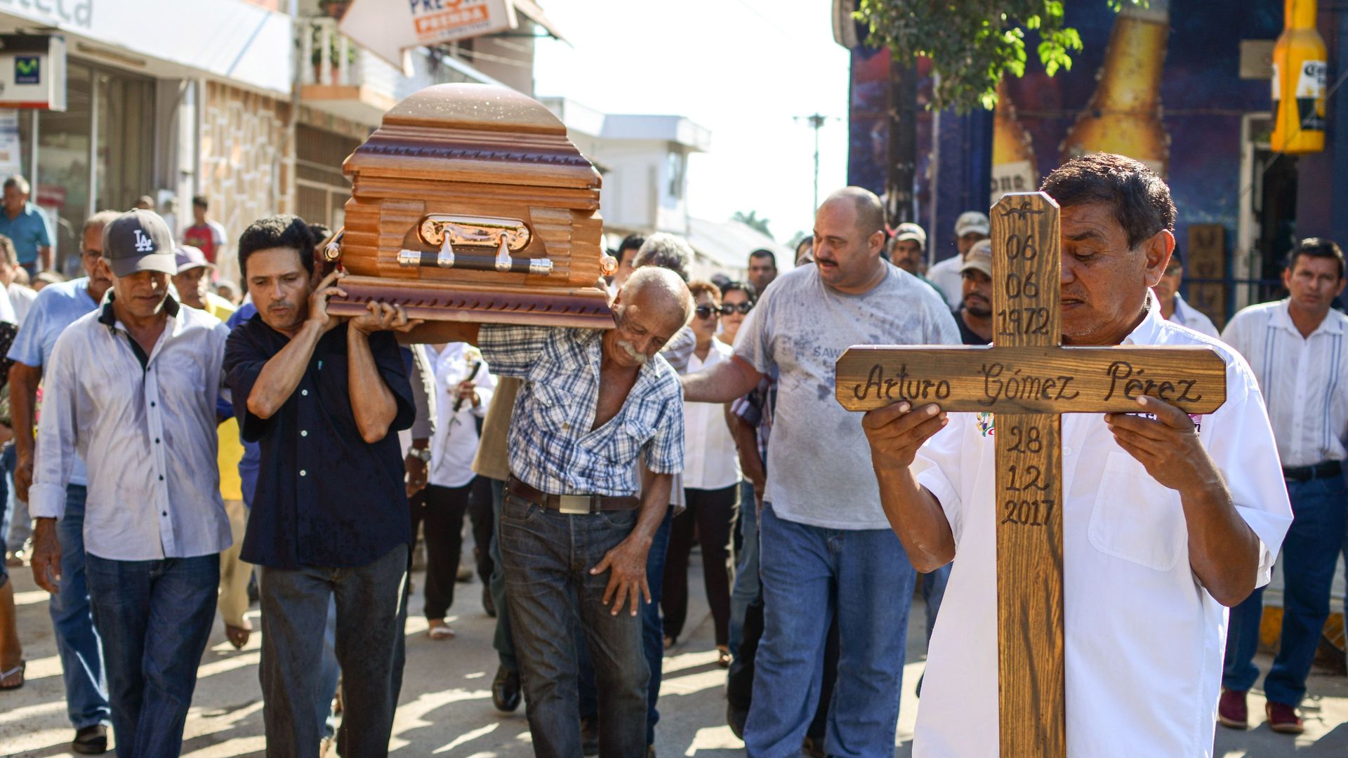 People carry a wooden coffin and wooden cross in Mexico down the street.