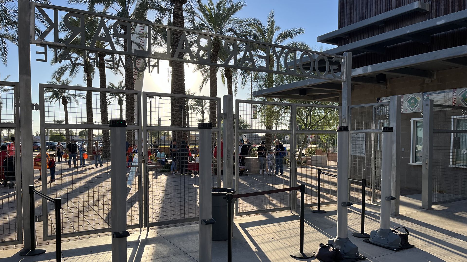 Two pairs of column-shaped electrical devices at the front gate of a baseball park. 