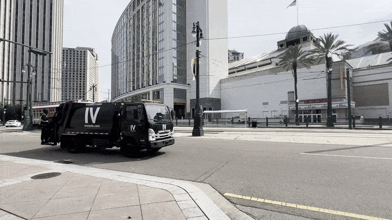 Image shows an IV Waste truck driving on Canal Street.
