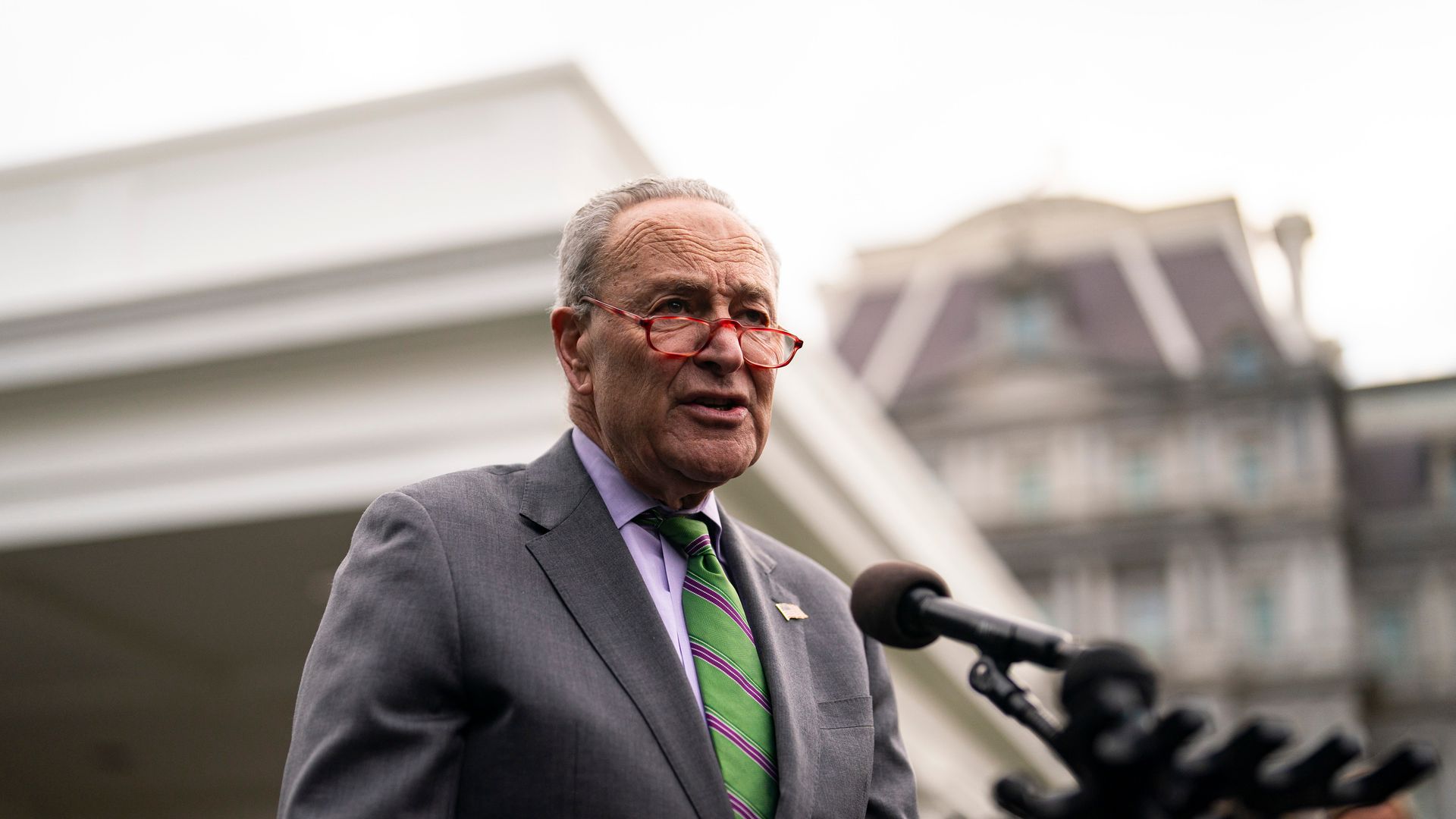 A person in a green tie speaks in front of a microphone