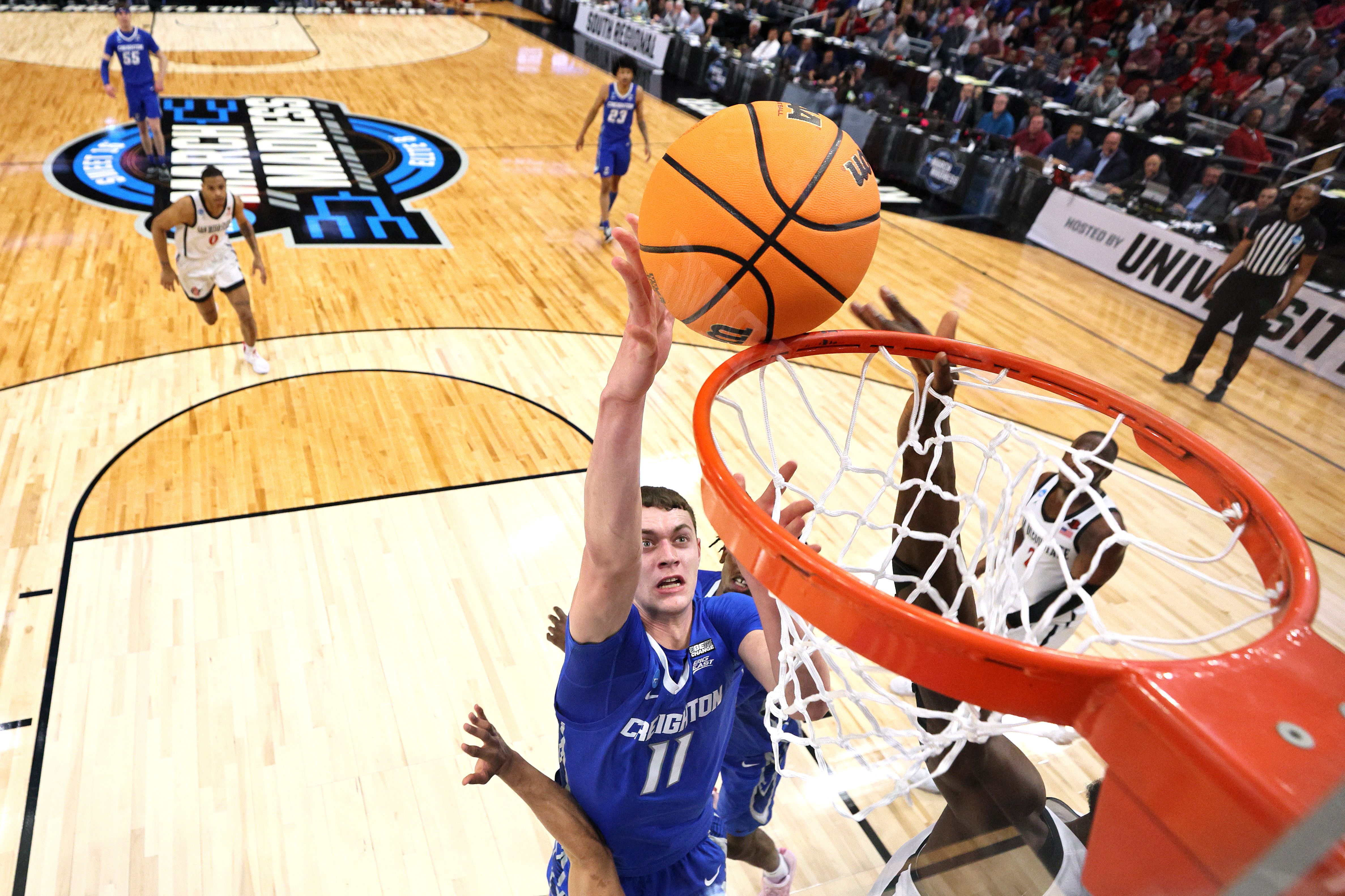 Photo of a man trying to shoot a basketball into a rim on a court 