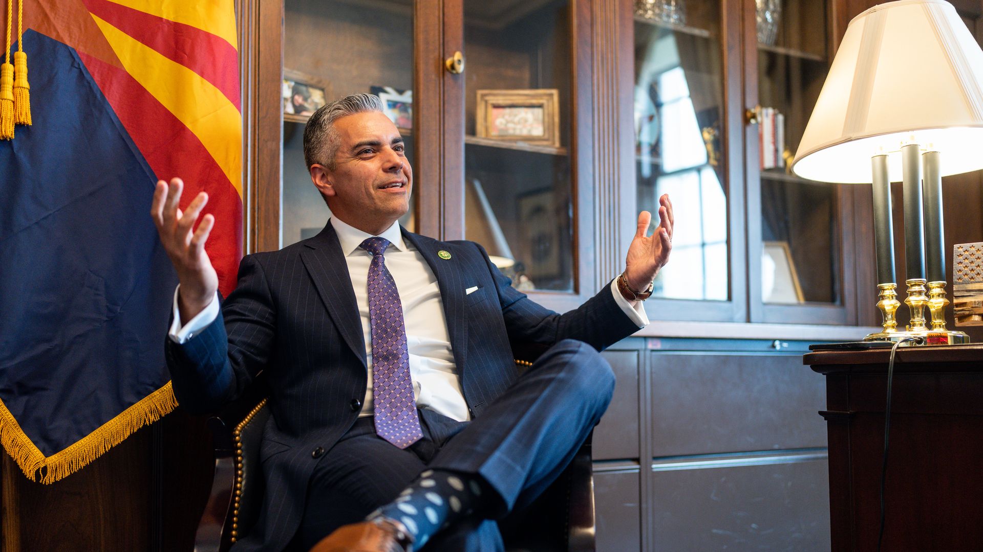 A man speaking in an office in front of an Arizona flag.