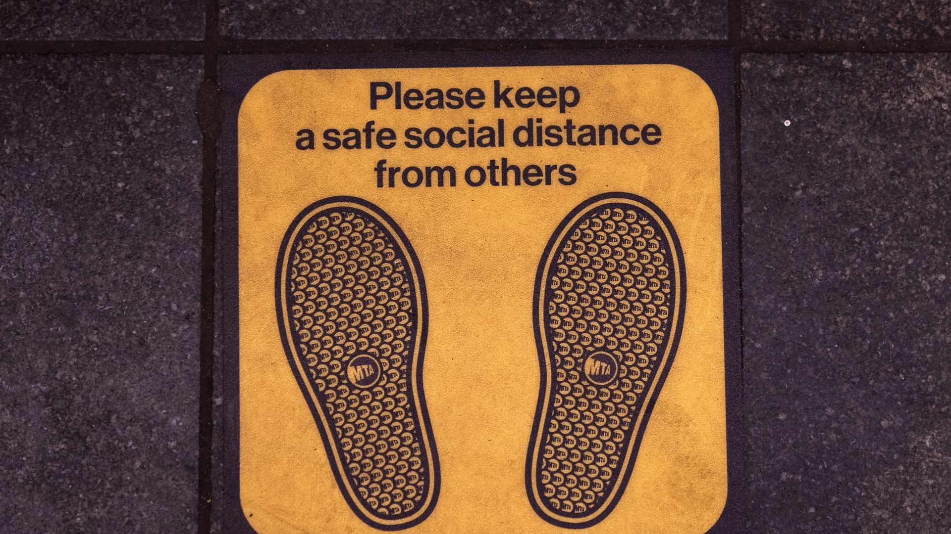  Signage on the floor of the Times Square subway platform asks commuter to maintain a safe social distance