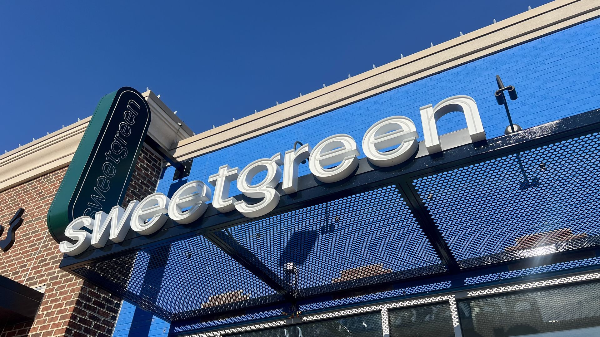 A pic of two sweetgreen signs up in front of a building