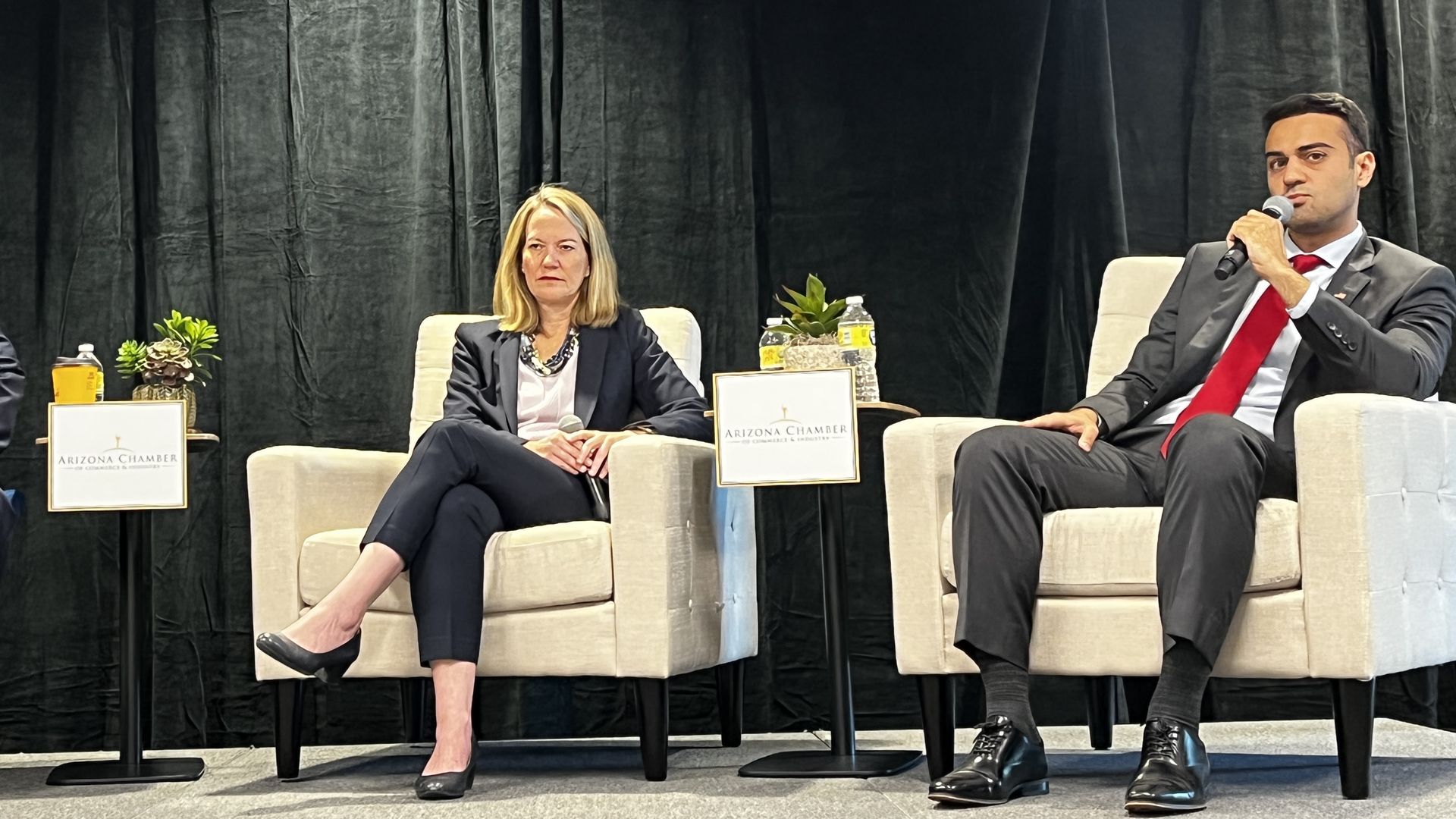 Two people sitting on a stage.
