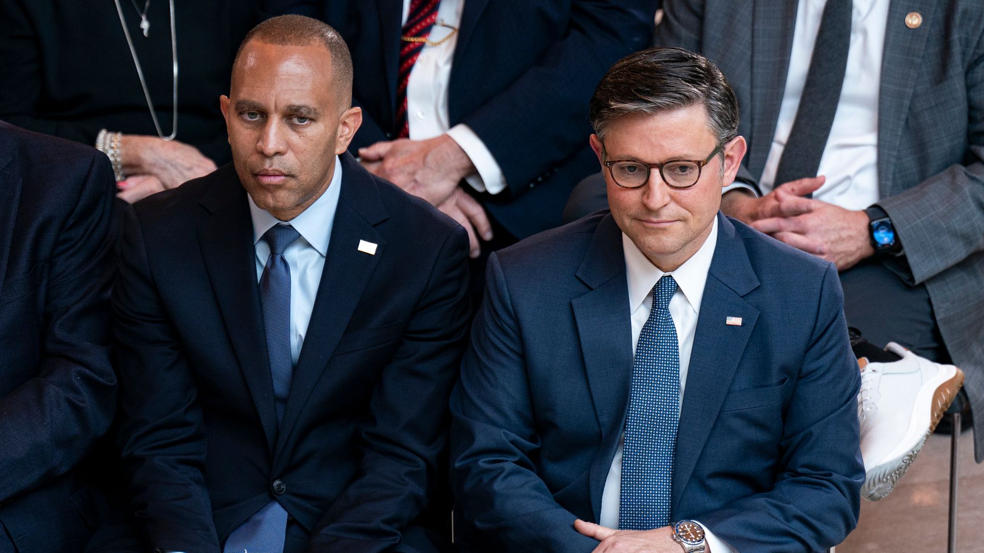 Reps. Hakeem Jeffries and Mike Johnson, wearing blue suits and sitting in chairs.