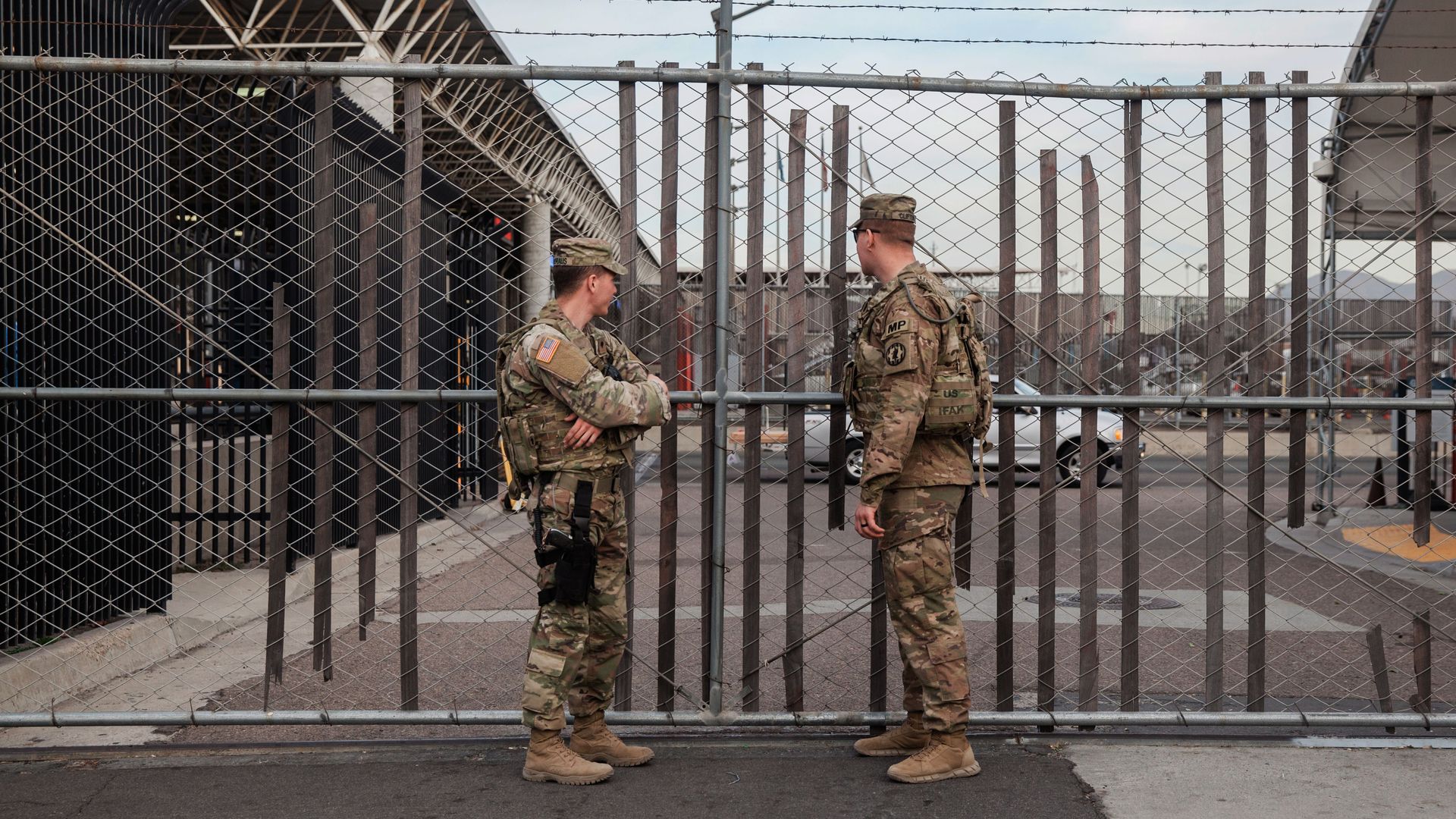 U.S. troops stand at a gate.