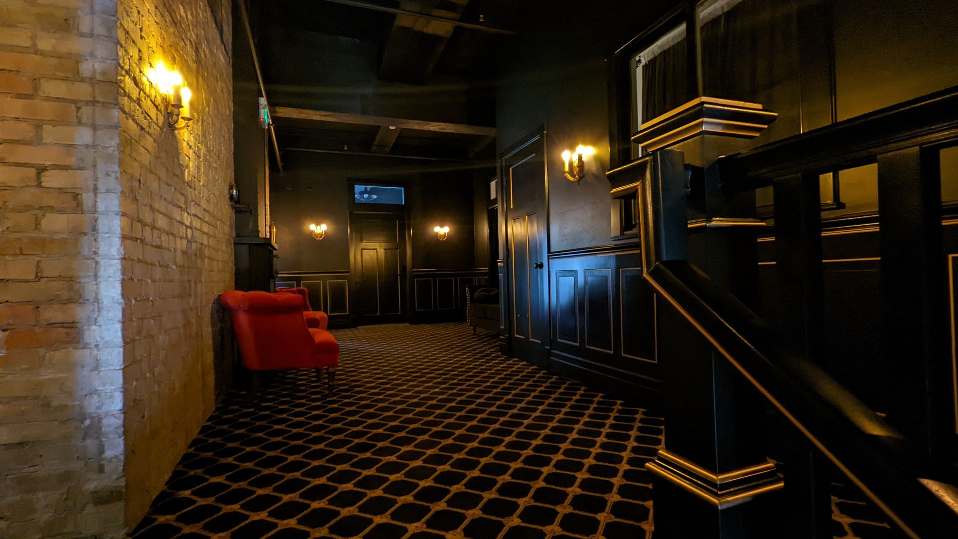 The hall of Key Suites has period-appropriate patterned carpet, exposed brick walls and painted molding with a red couch.