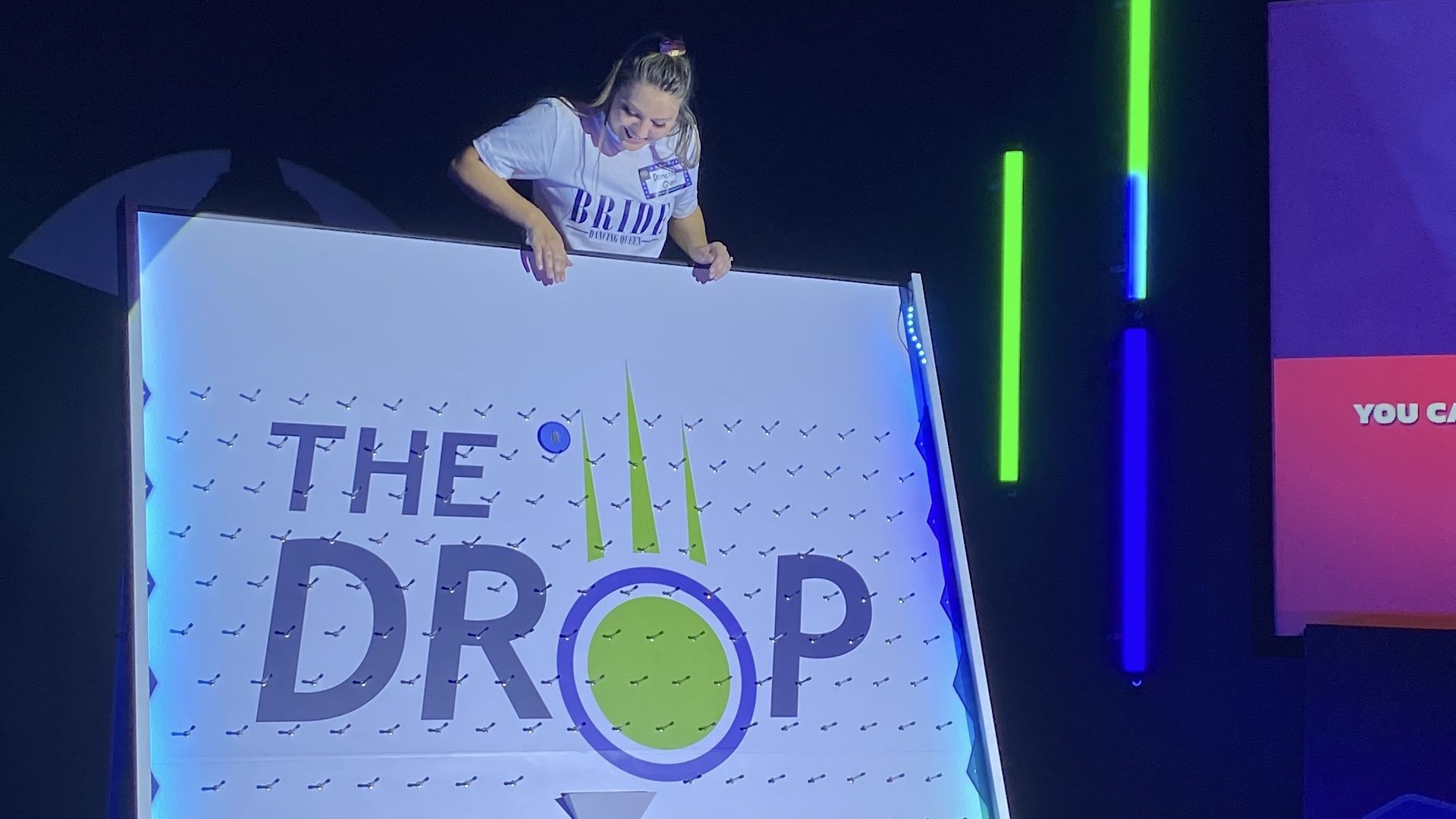 A woman dropping a puck on a board that says, "The Drop."