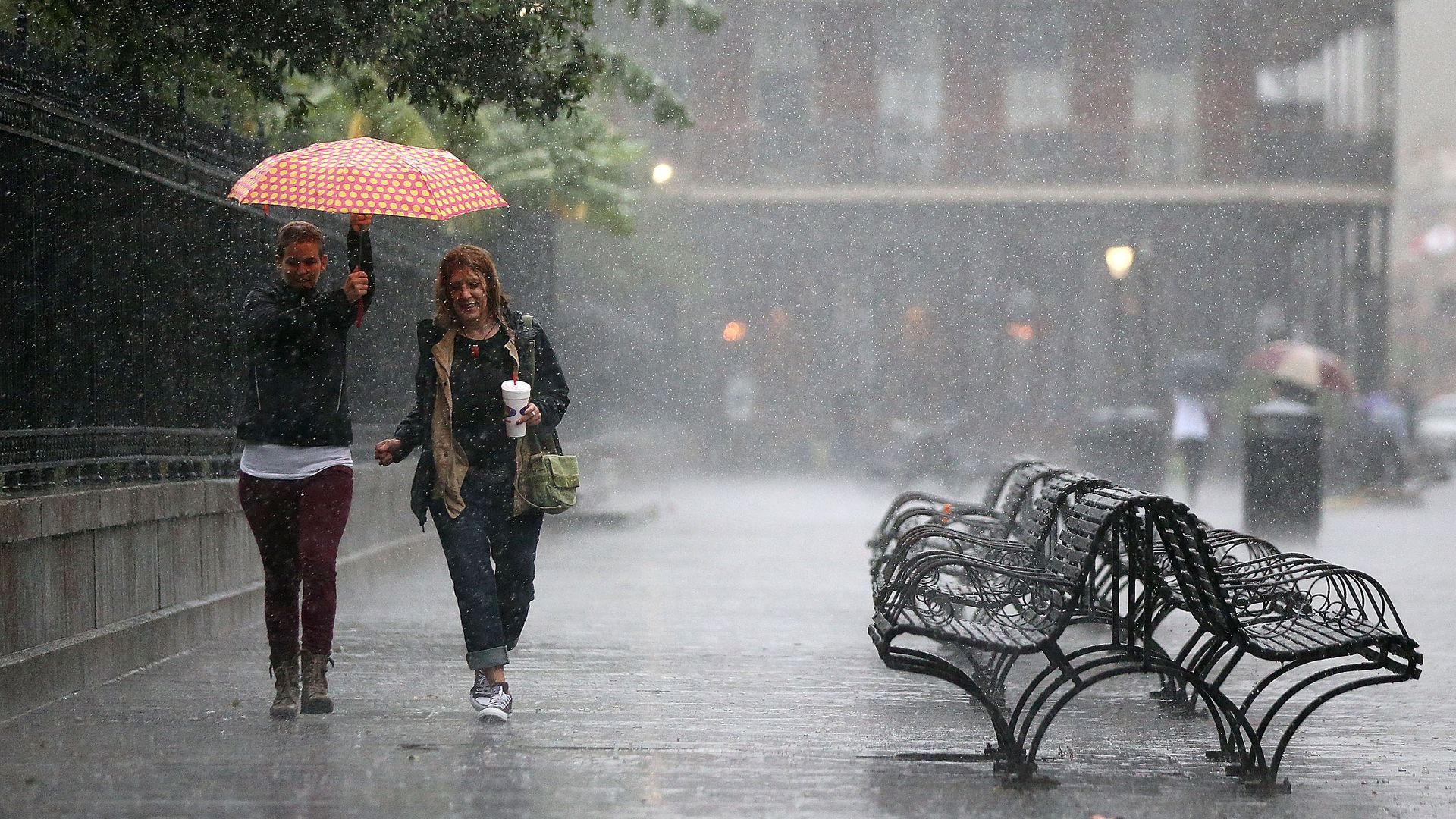 Photo shows two women walking in the rain in Jackson Square.