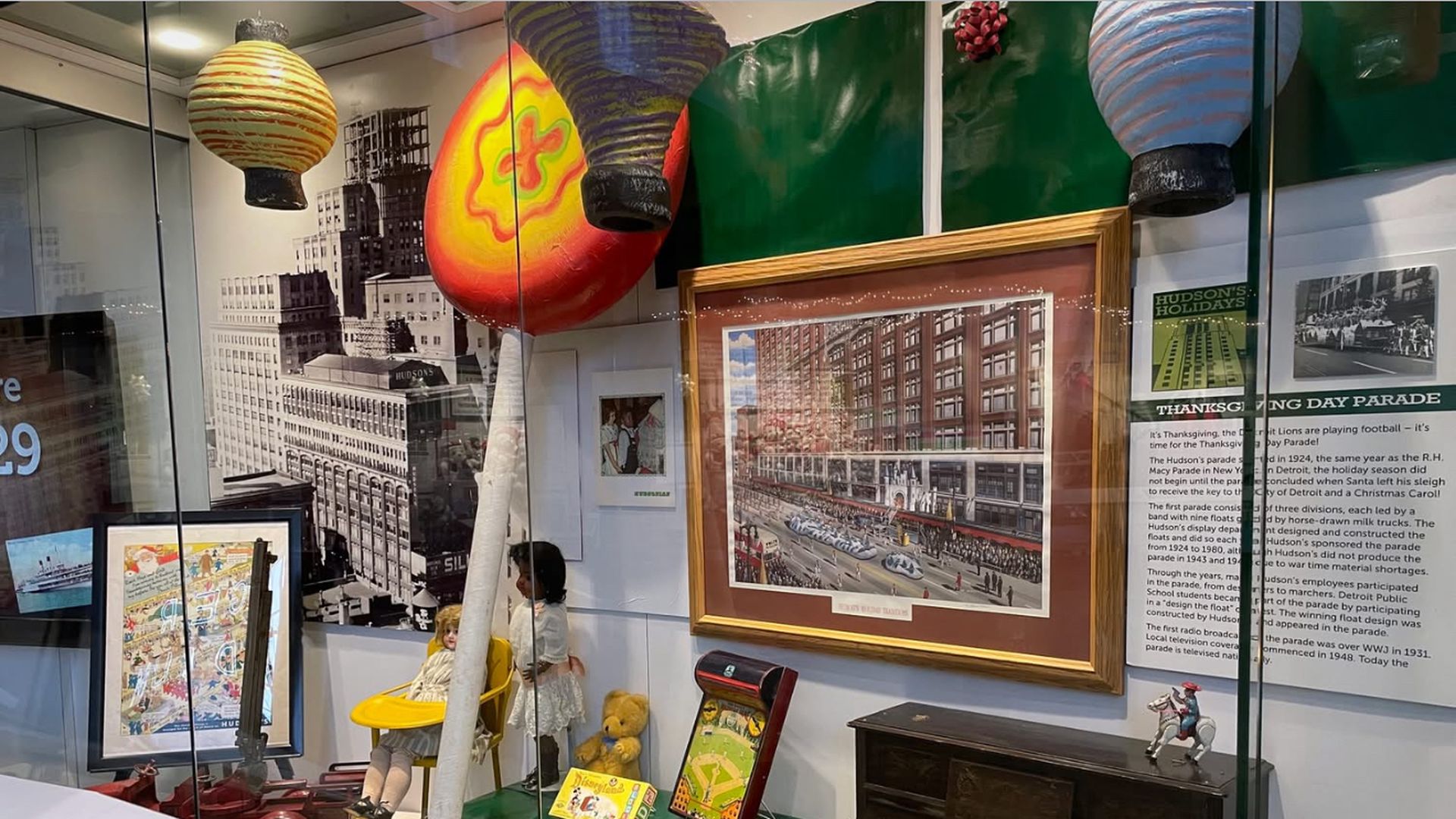 Museum display featuring vintage toys and framed historic photos and posters about the Hudson's Thanksgiving Day Parade.