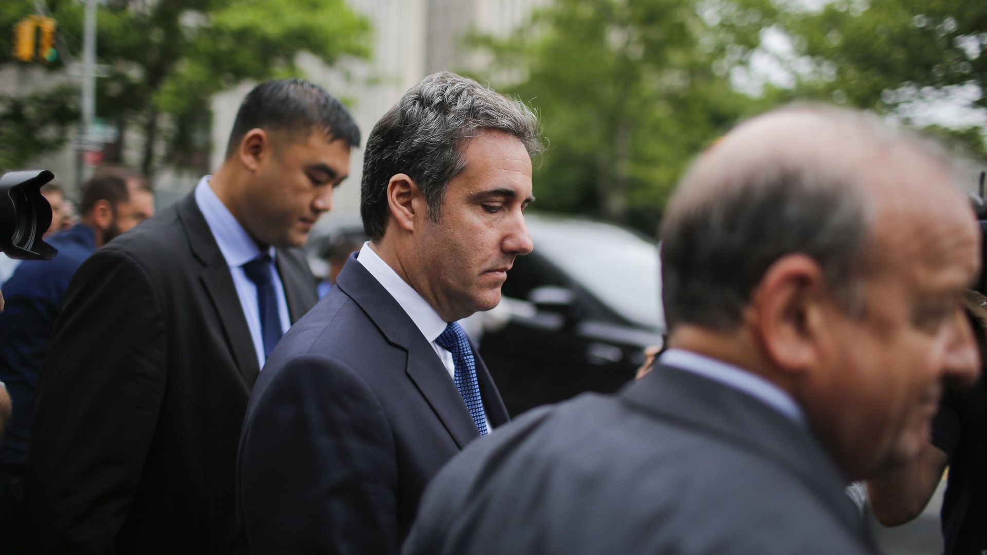 Michael Cohen looks down as he's escorted out of a courthosue