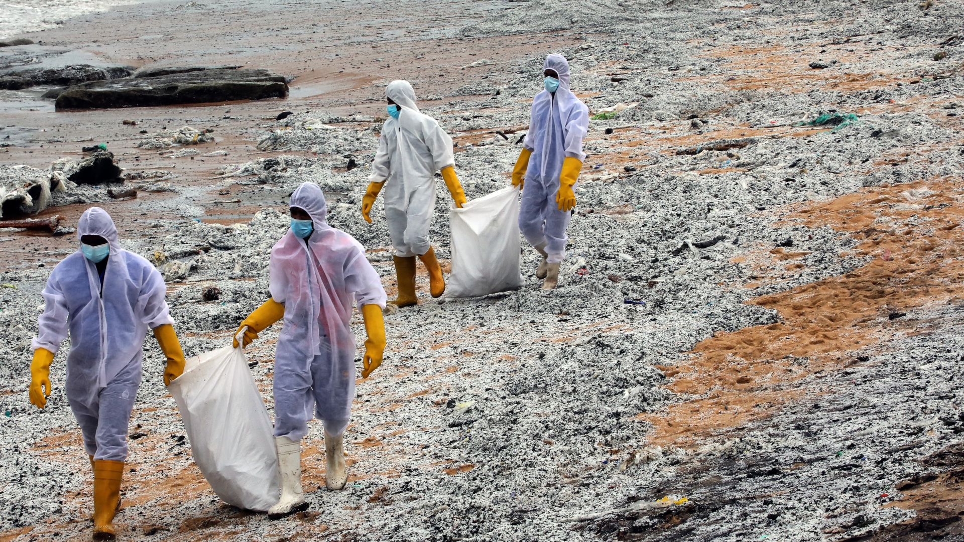 Sri Lanka Navy personnel in protective clothing clearing the debris on the beaches of Sri Lanka