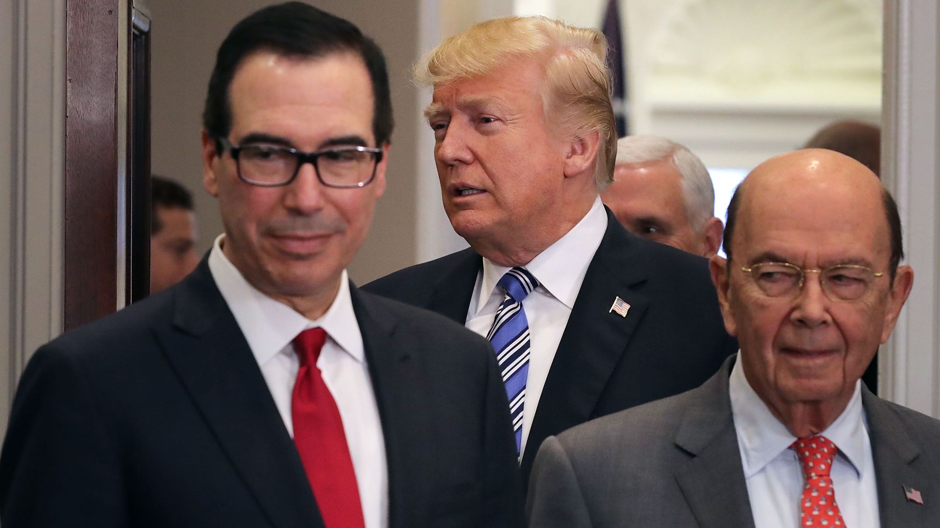 Steve Mnuchin, President Trump and Wilbur Ross all shuffle through a doorway