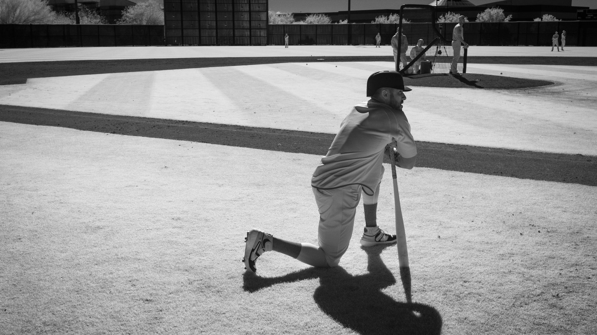 A baseball player watches live batting practice