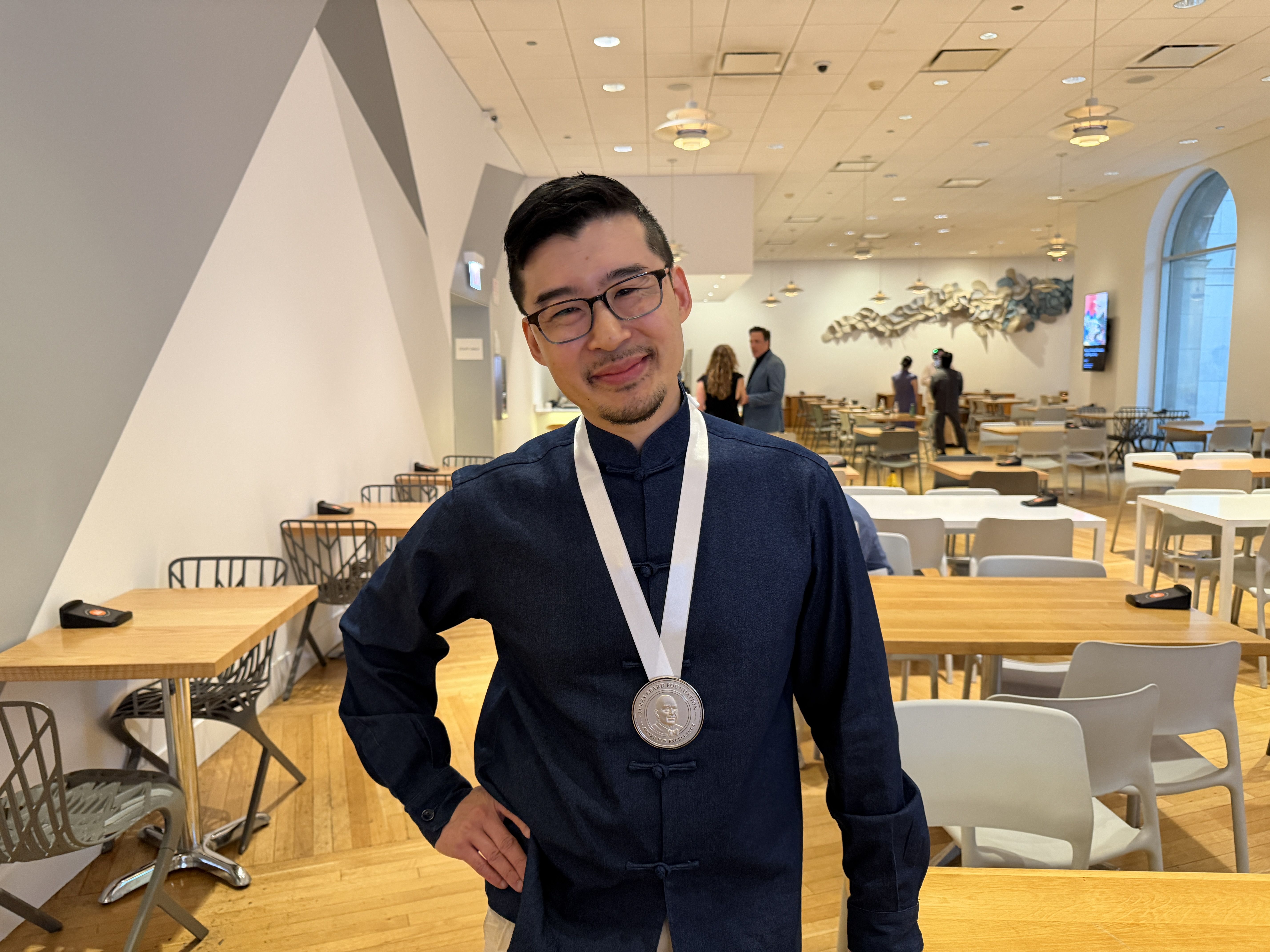 Guy with blue jacket and award around neck
