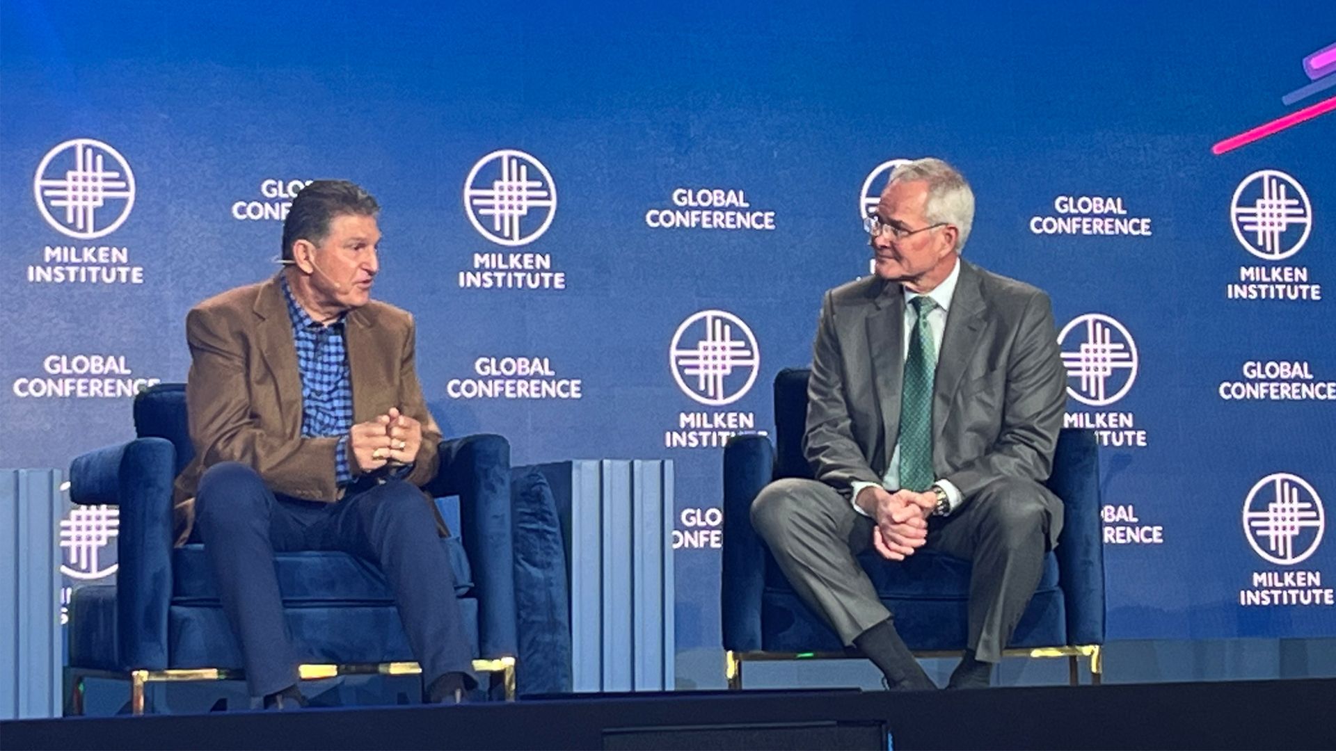 A photo of Sen. Joe Manchin, R-W.Va., and Exxon CEO Darren Woods, speaking at the Milken Institute Global Conference,