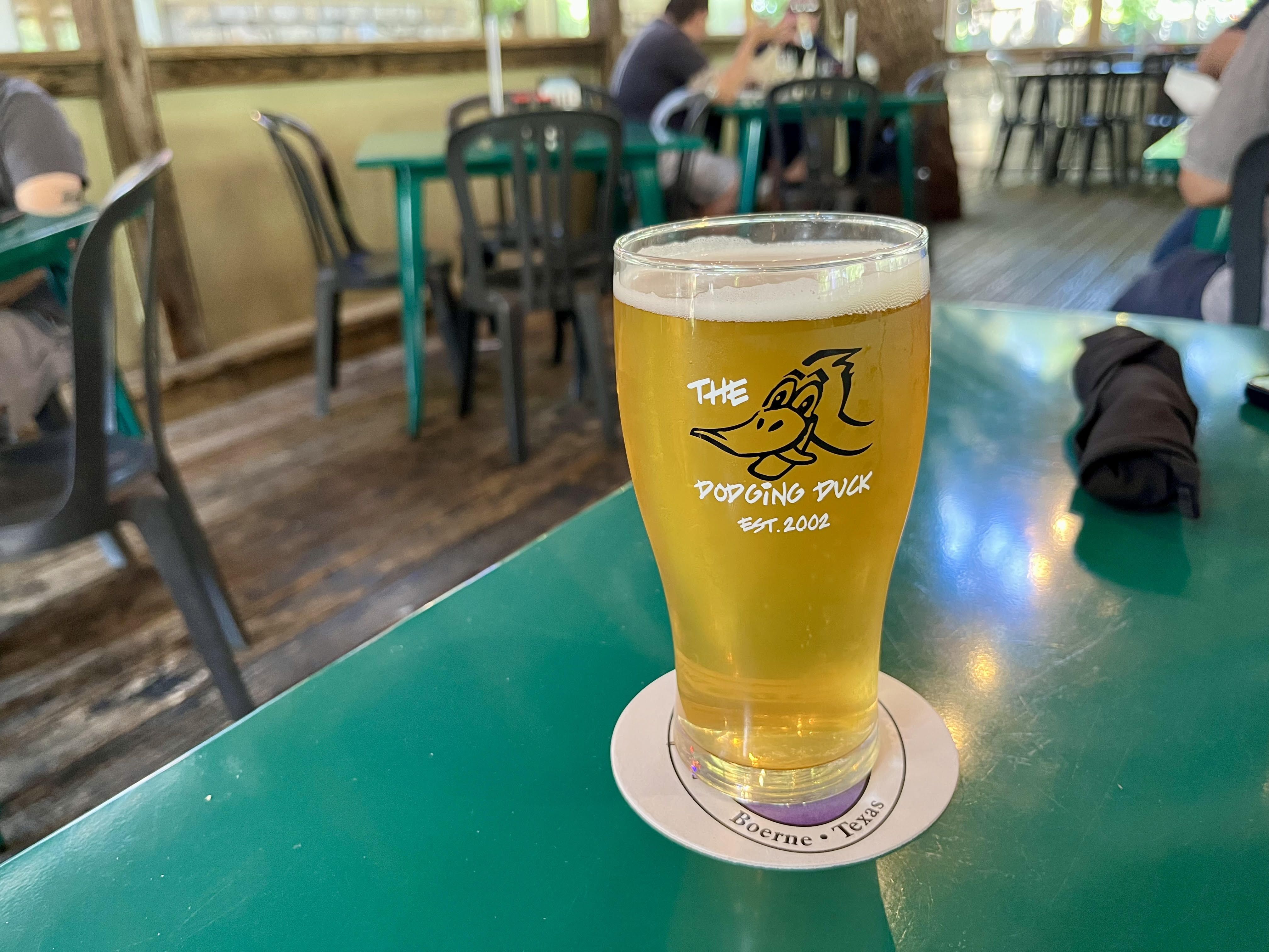A light beer sits on a green table.