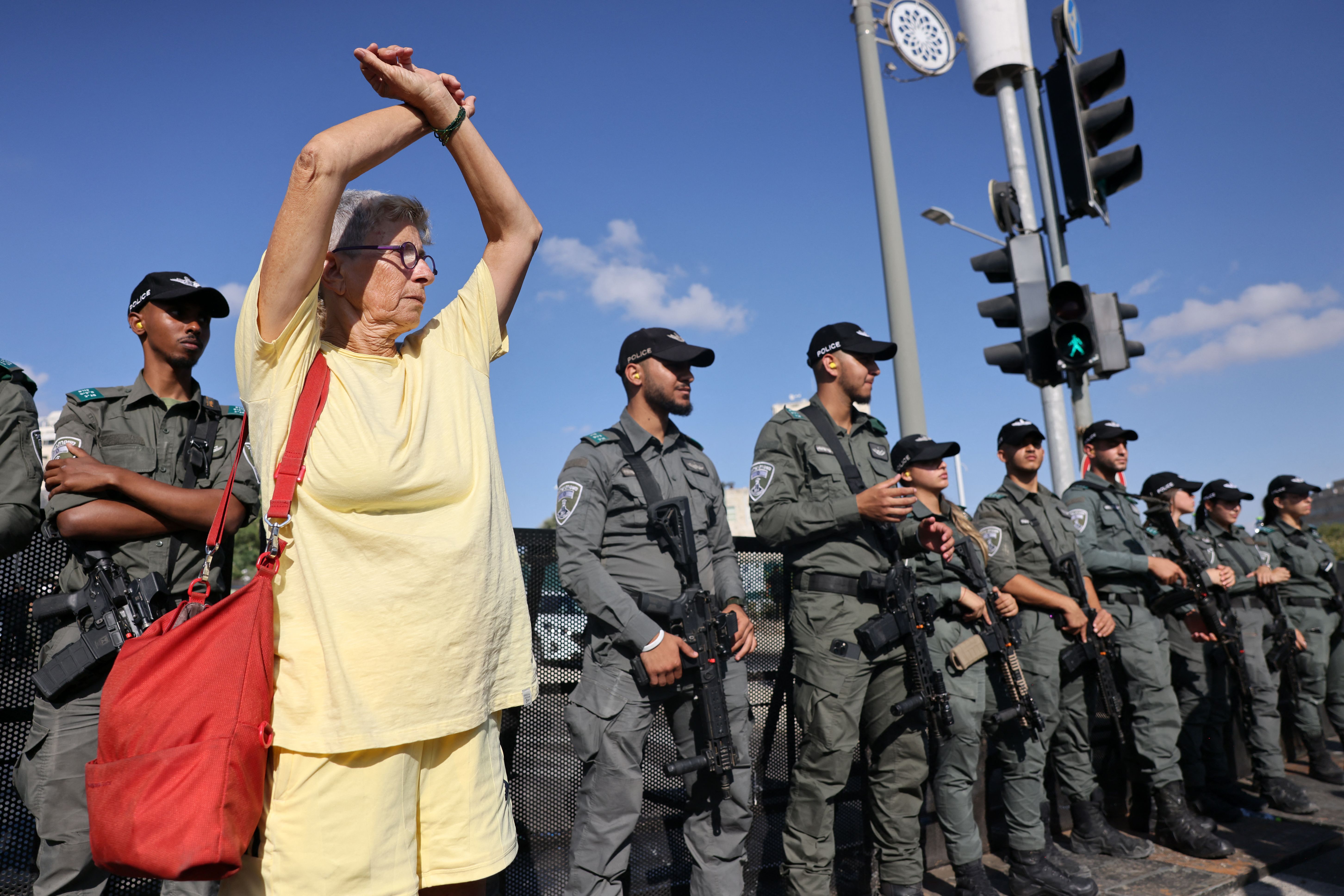 A woman crosses her wrists in front of Israeli security forces standing guard during a protest by relatives and supporters of Israeli hostages taken captive in the Gaza Strip since the October 7 attacks by Palestinian Hamas militants, outside the prime minister's office in Jerusalem on September 1.