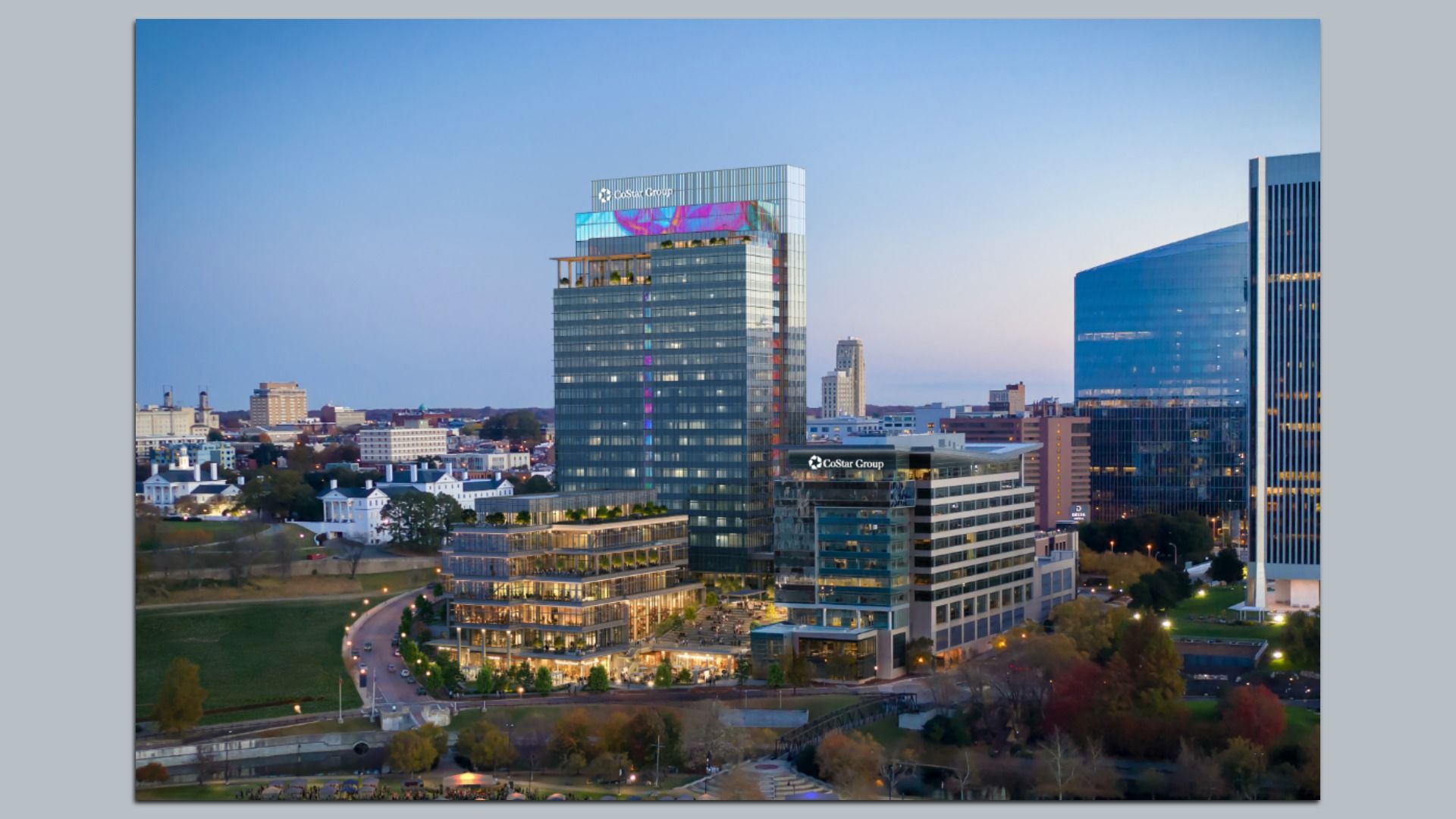 City skyline featuring modern glass office towers, including a tall central building with the CoStar Group logo; a blue glass complex to the right, with a park and houses in the foreground.